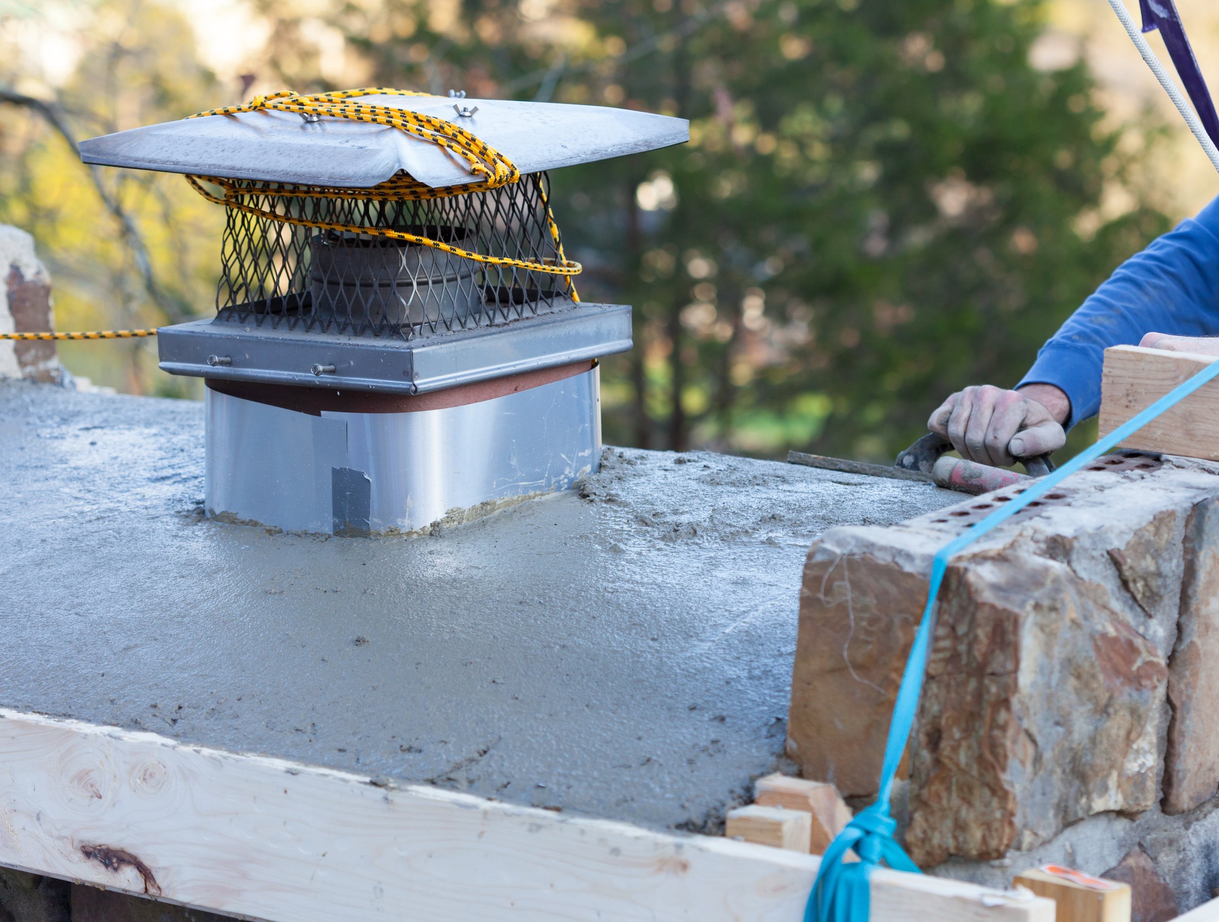 Man using cement to repair the crown of a house chimney