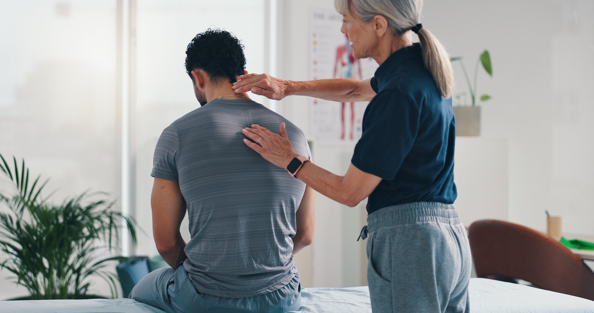 Physiotherapy, back massage and patient man at consultation for spinal problem or inflammation. Person, chiropractor and touch for injury, rehabilitation and recovery of muscle damage clinic bed