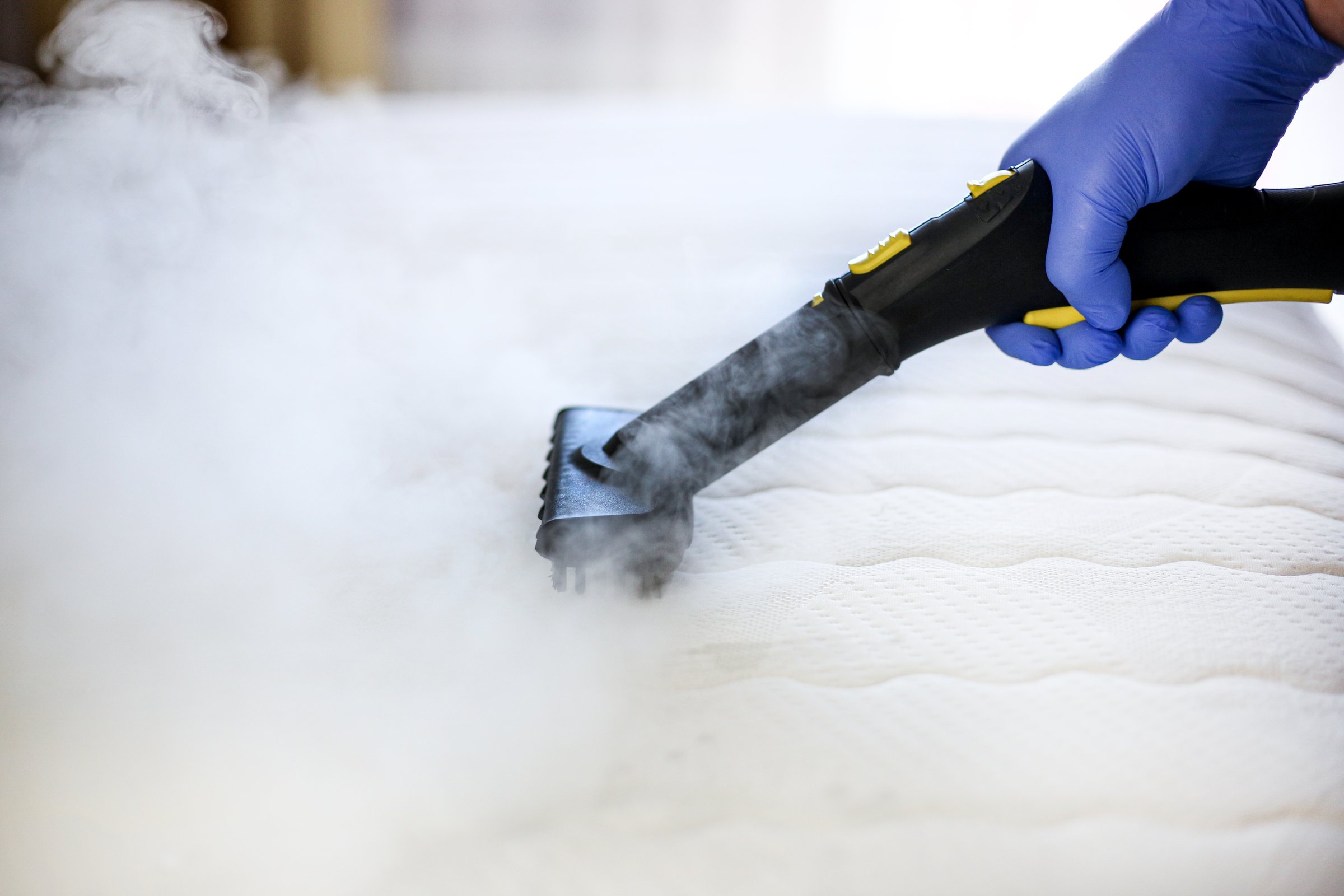 Cleaning and disinfection of the mattress in the bedroom with hot steam. Professional cleaning process