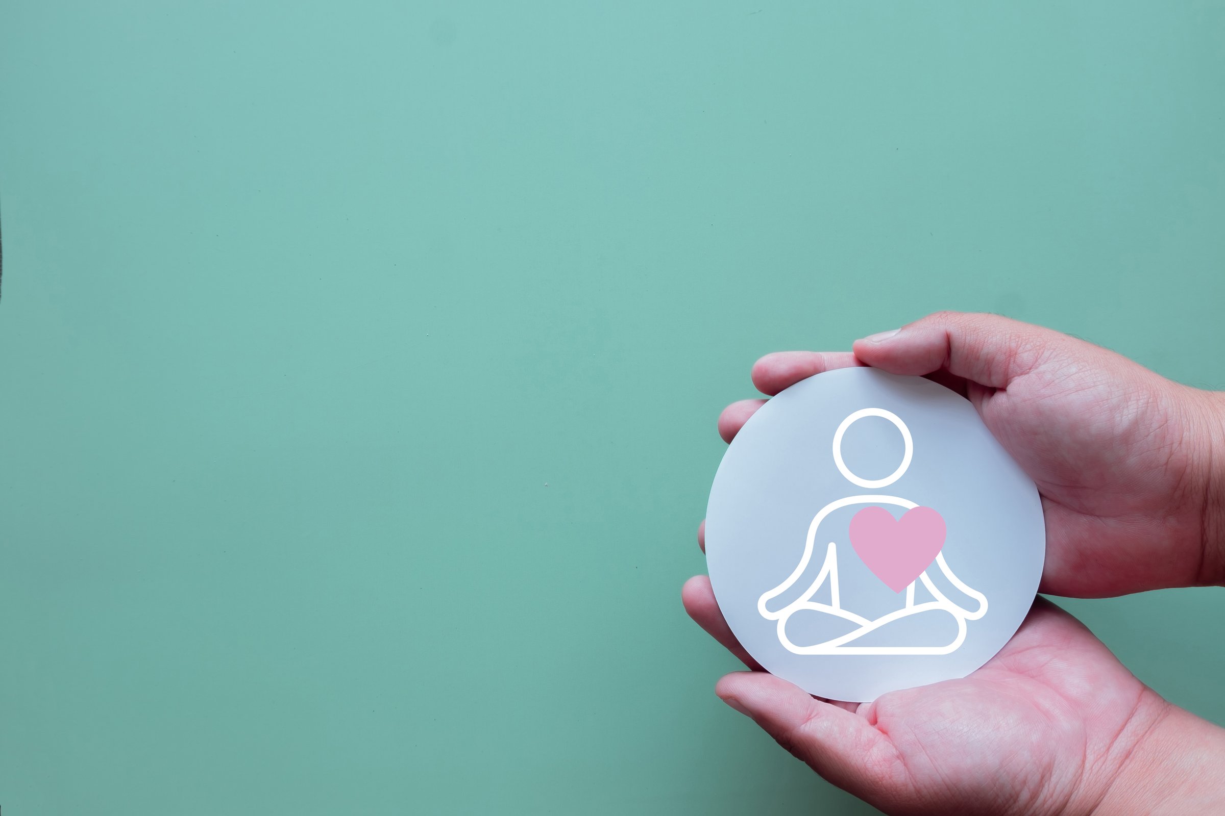 Hands hold a meditation icon on green background with Copy space., A concept for mental health,wellness,self-care.,A symbol for mindfulness, stress relief, inner peace, and emotional well-being.