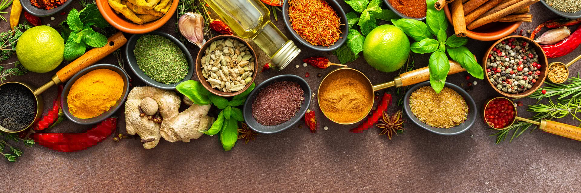 A rich palette of colorful spices and herbs, resting on a brown background, radiating freshness and aroma, perfect for gourmet inspiration, banner
