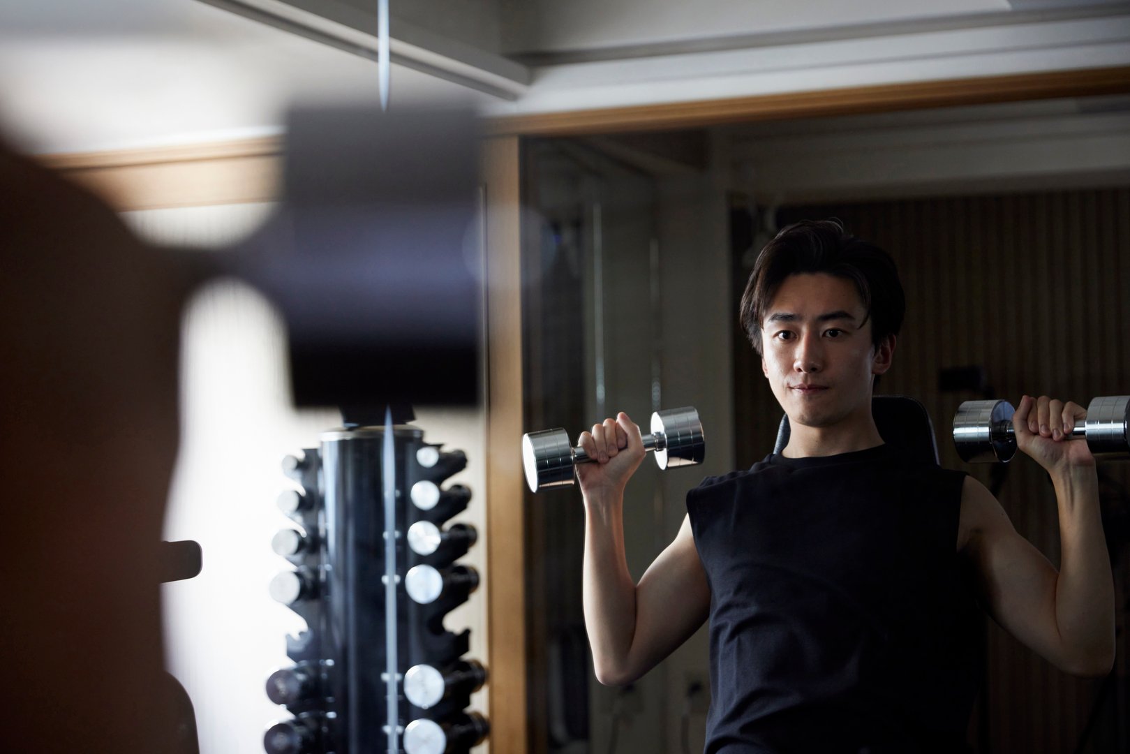 Young Japanese man in sportswear doing strength training at a fitness gym