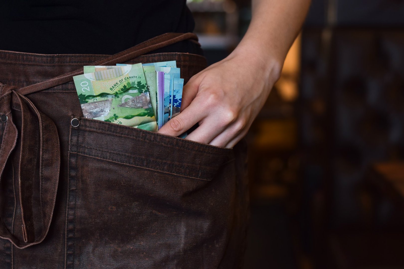 Closeup on waitress hands holding Canadian paper cash money tips