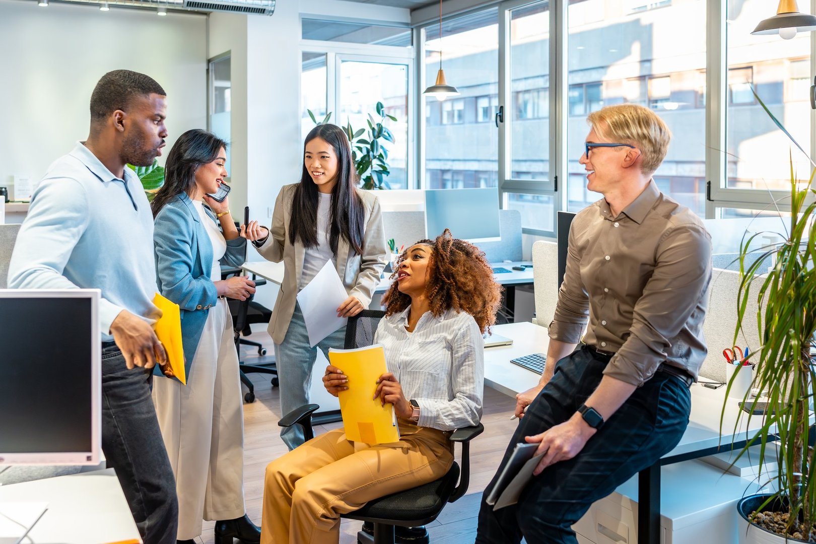 Multi-ethnic colleagues discussing project details, sharing ideas, and working together in a modern coworking office