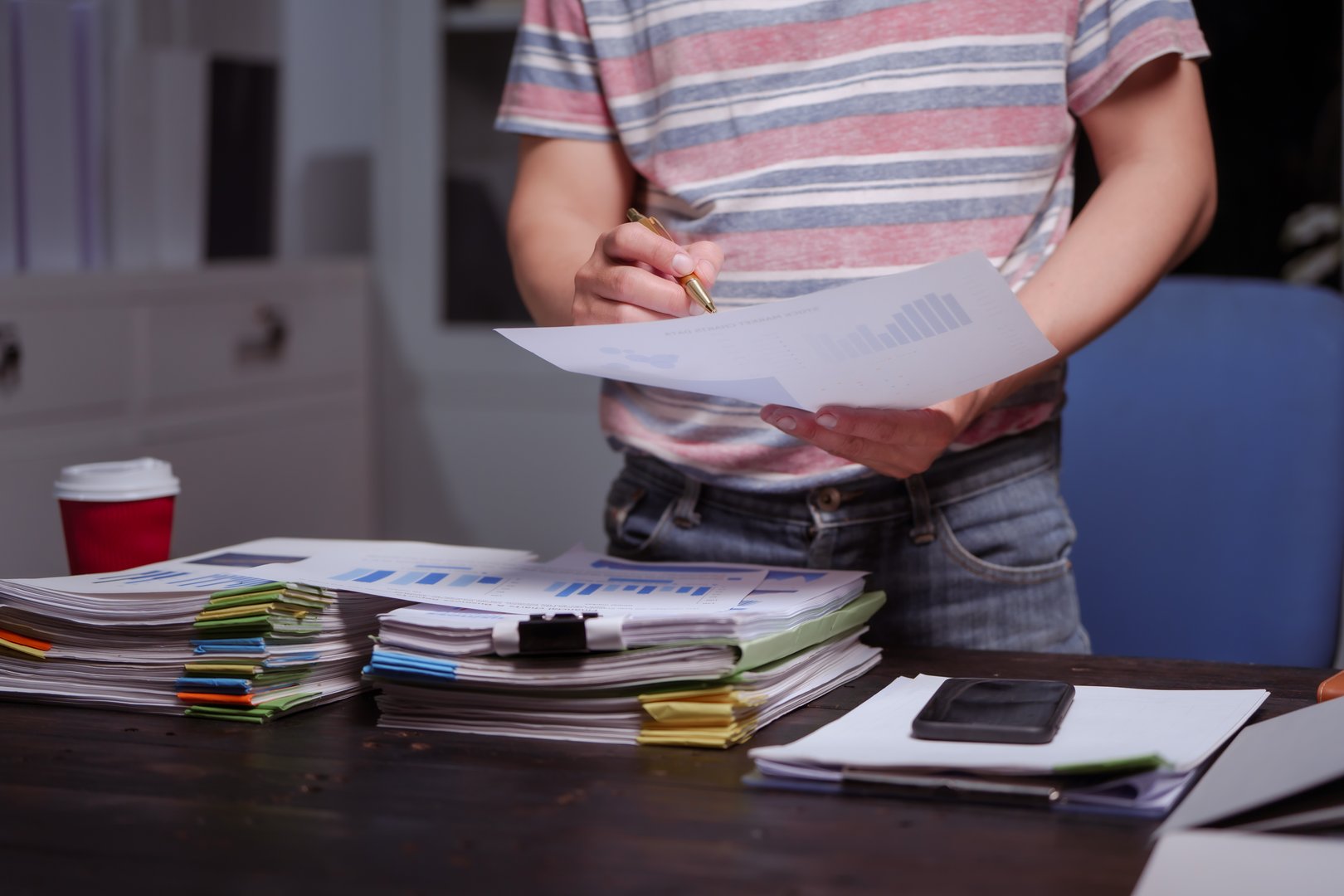 A man sits at his desk at home at night, working on his laptop. He views charts, checks documents, and analyzes financial data, focusing on investments, stock trading, and shareholder rights