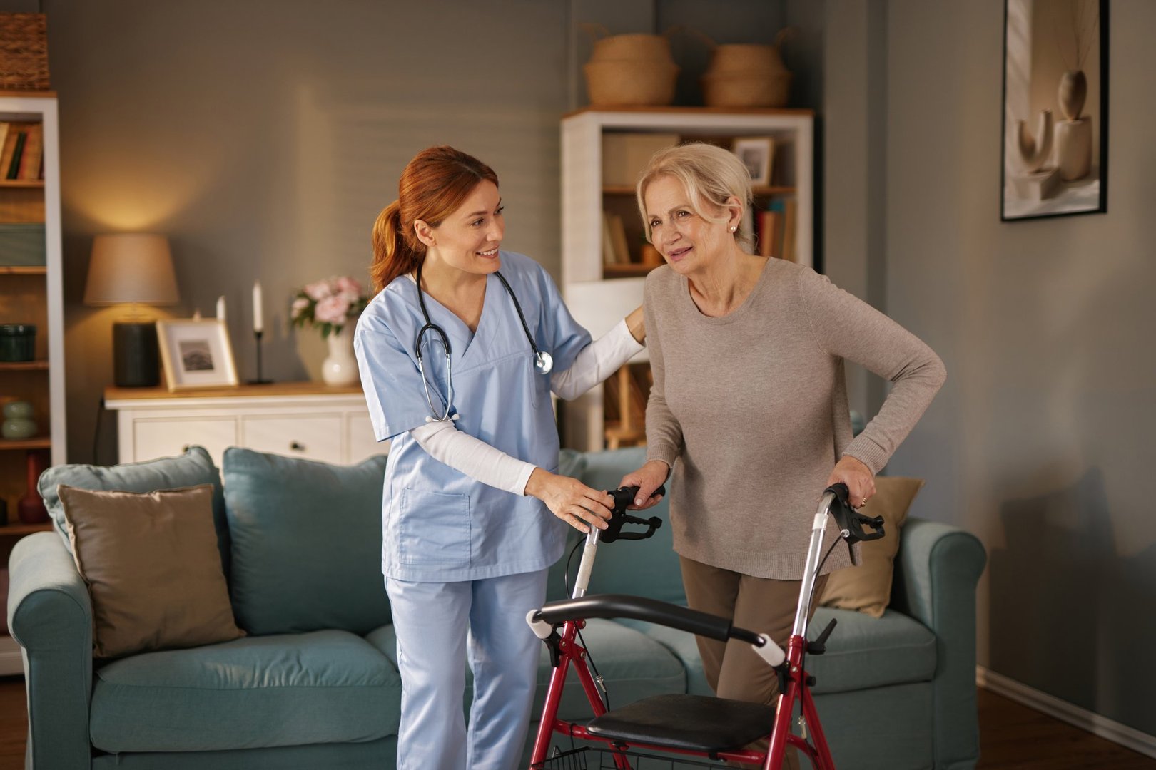 Smiling nurse supports senior woman learning to walk with walker in her living room