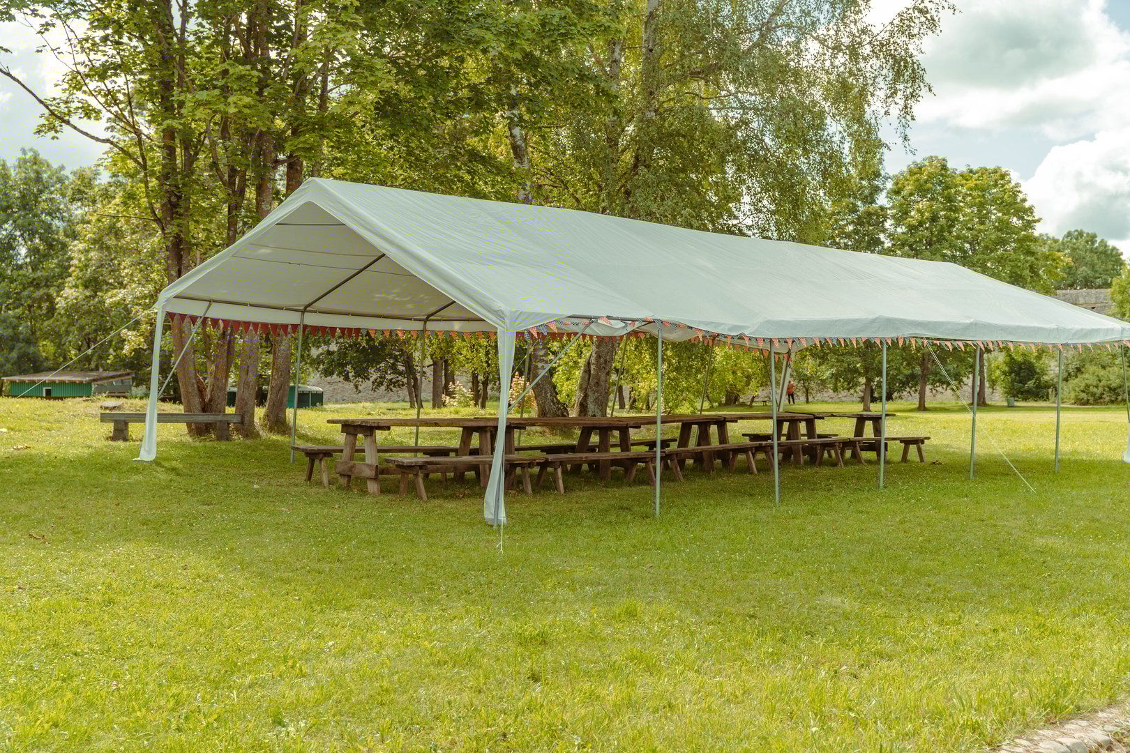 A spacious tent with benches stands ready for an outdoor event.