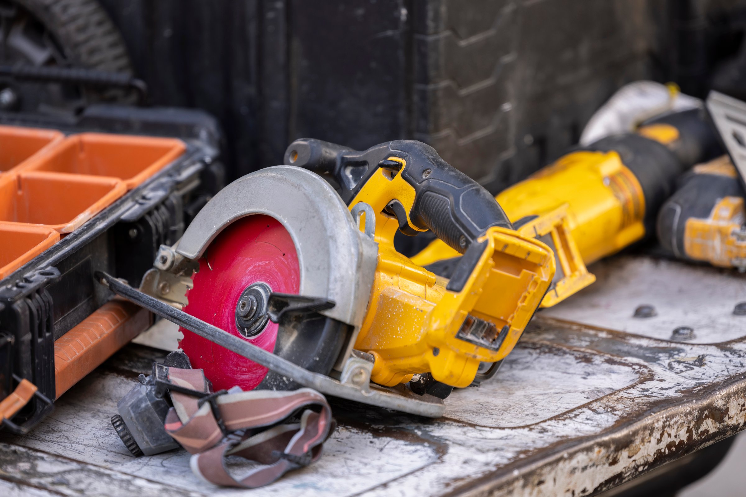 A circular saw, drills and other construction tools and equipment lay in the back of a truck