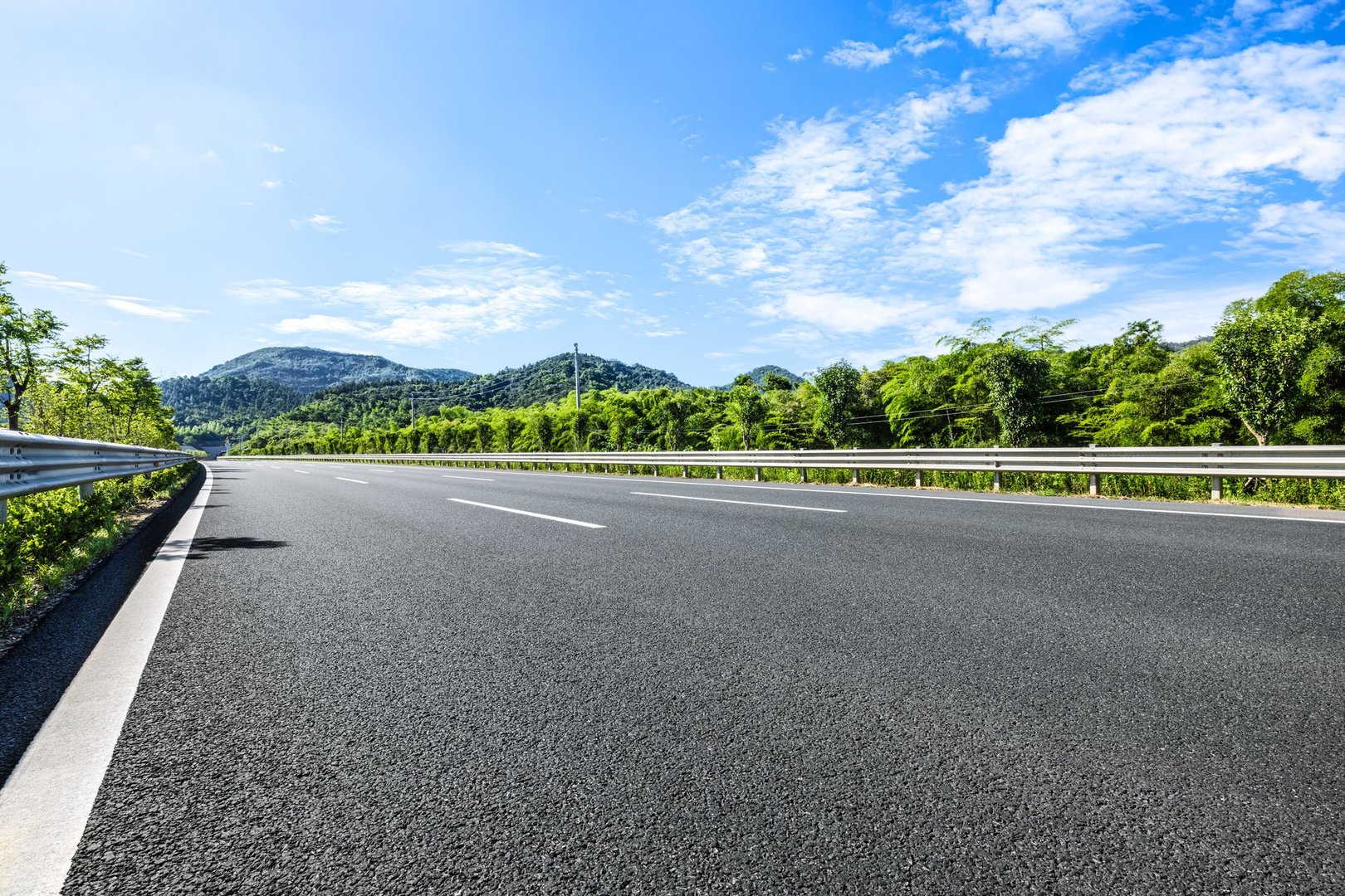 Empty asphalt road curves through landscape with mountain range
