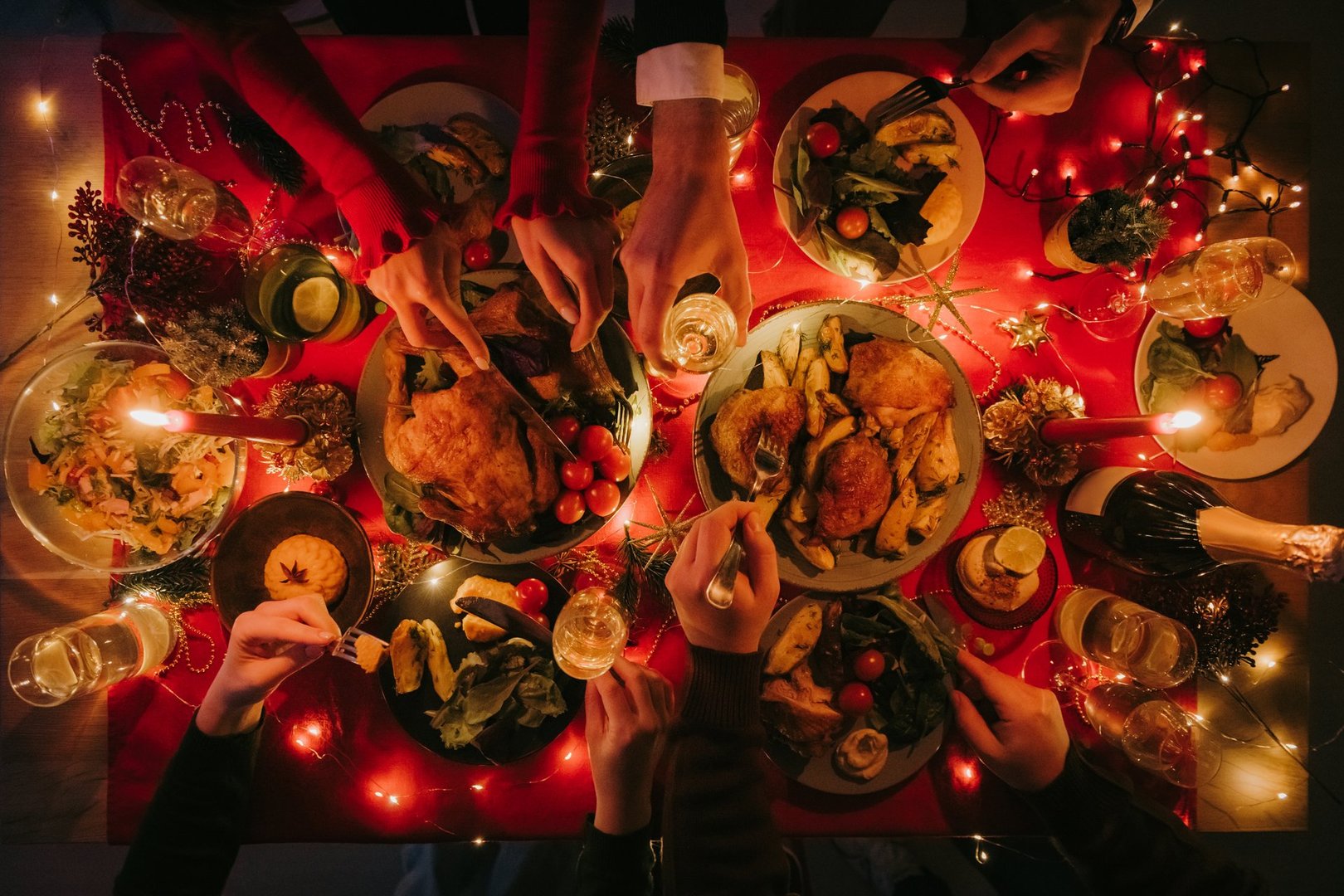 Top view of people enjoying variety of festive dishes while having Christmas dinner at the decorated table