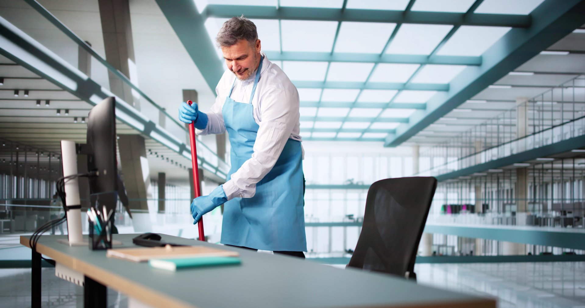 Male Janitor Cleaning Floor With Mop In Office