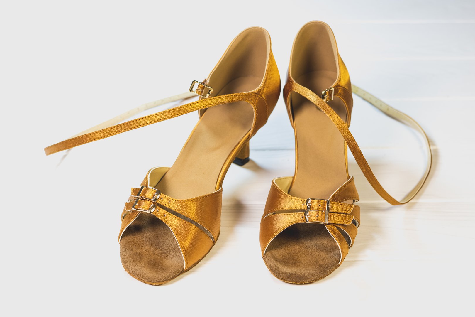Gold colored women's dancing shoes on white background.
