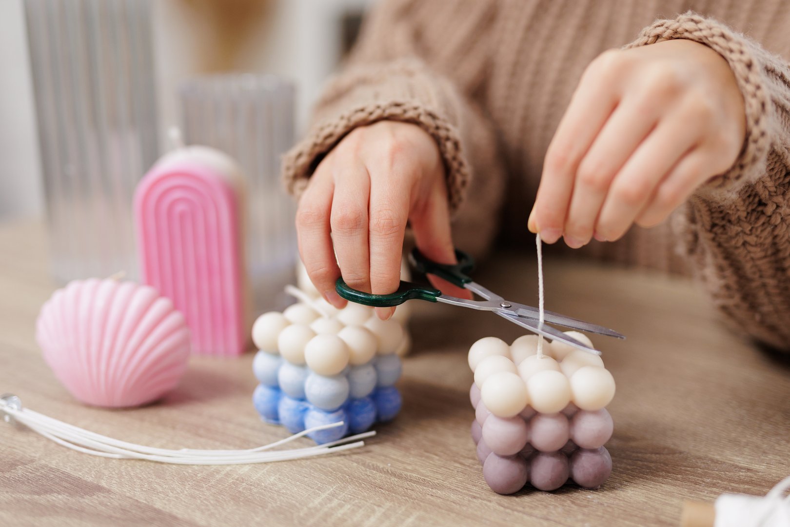 Close up of female hands cutting wick of bauble candle on table