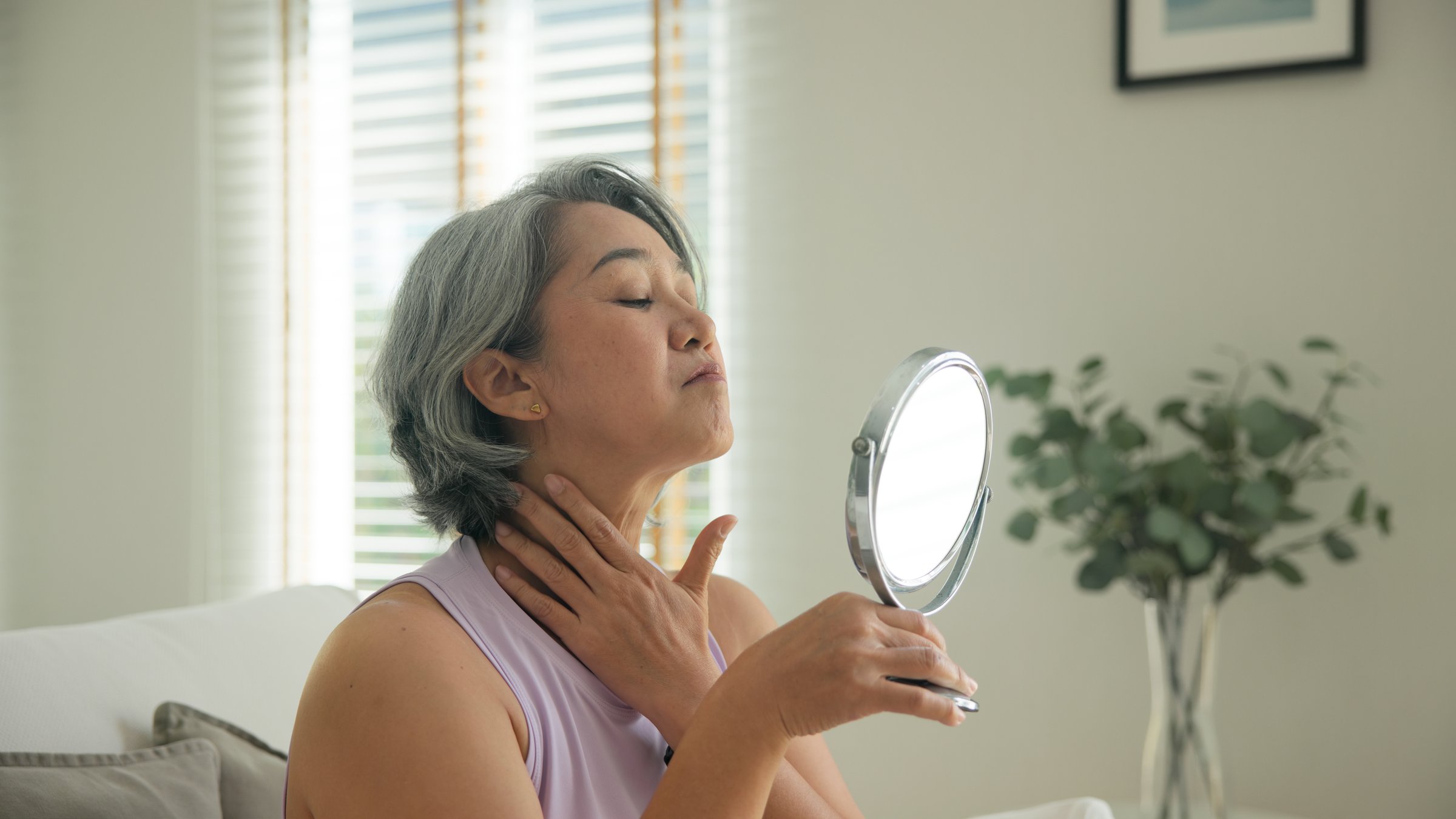 Asia adult people middle age old woman look at mirror dry skin face hand touch neck cheek stress sad at home elder health care aging beauty issue. Asian female aged eye botox filler plastic surgery.