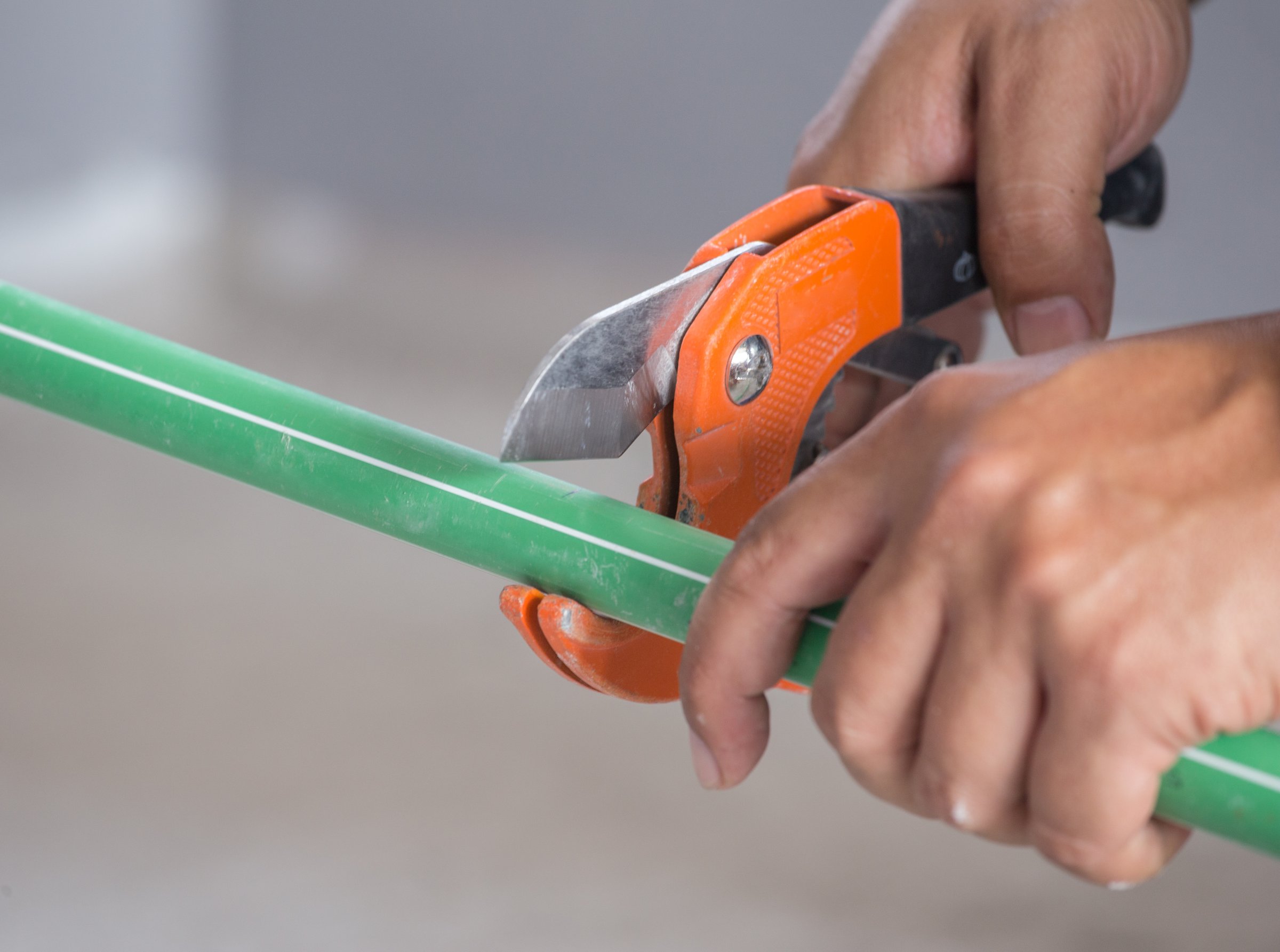 hand of working cutting green PPR plumbing pipe