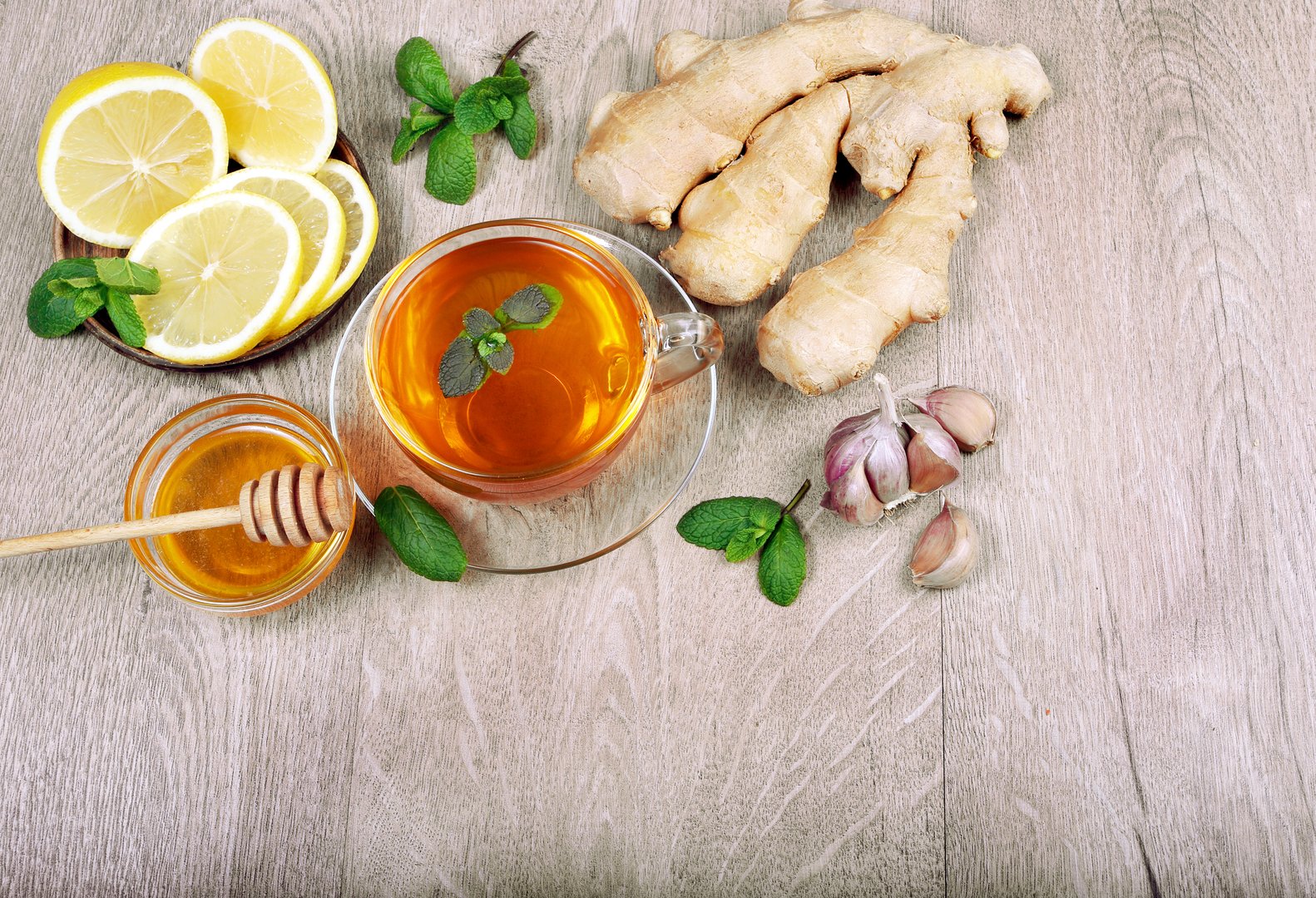 Honey, ginger, lemon, garlic and a cup of tea on a wooden table. for cold and flu