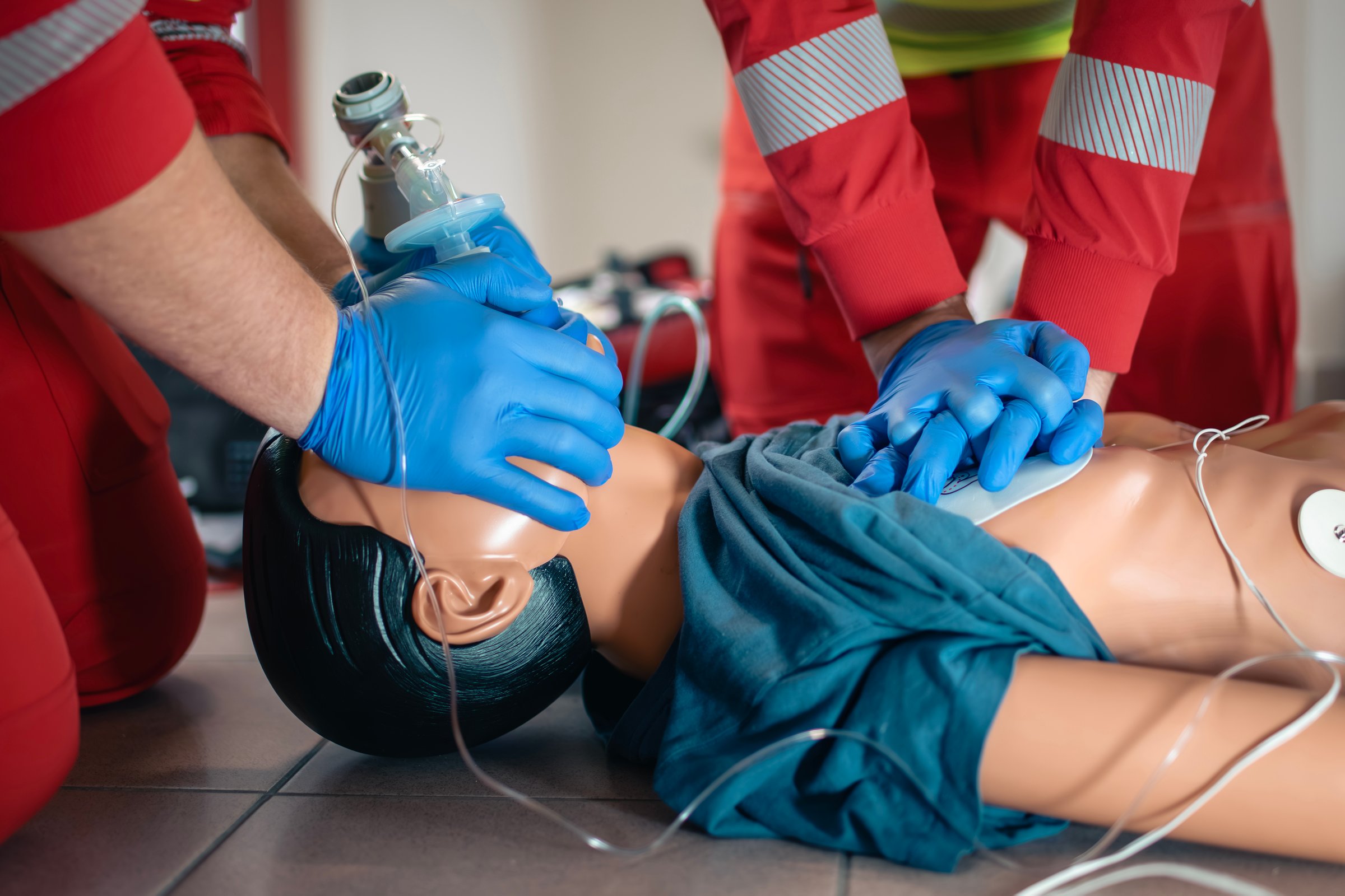 Hands of paramedic and doctor during resuscitation. Team of emergency medical service during CPR training on dummy. Themes rescue, urgency and health care.