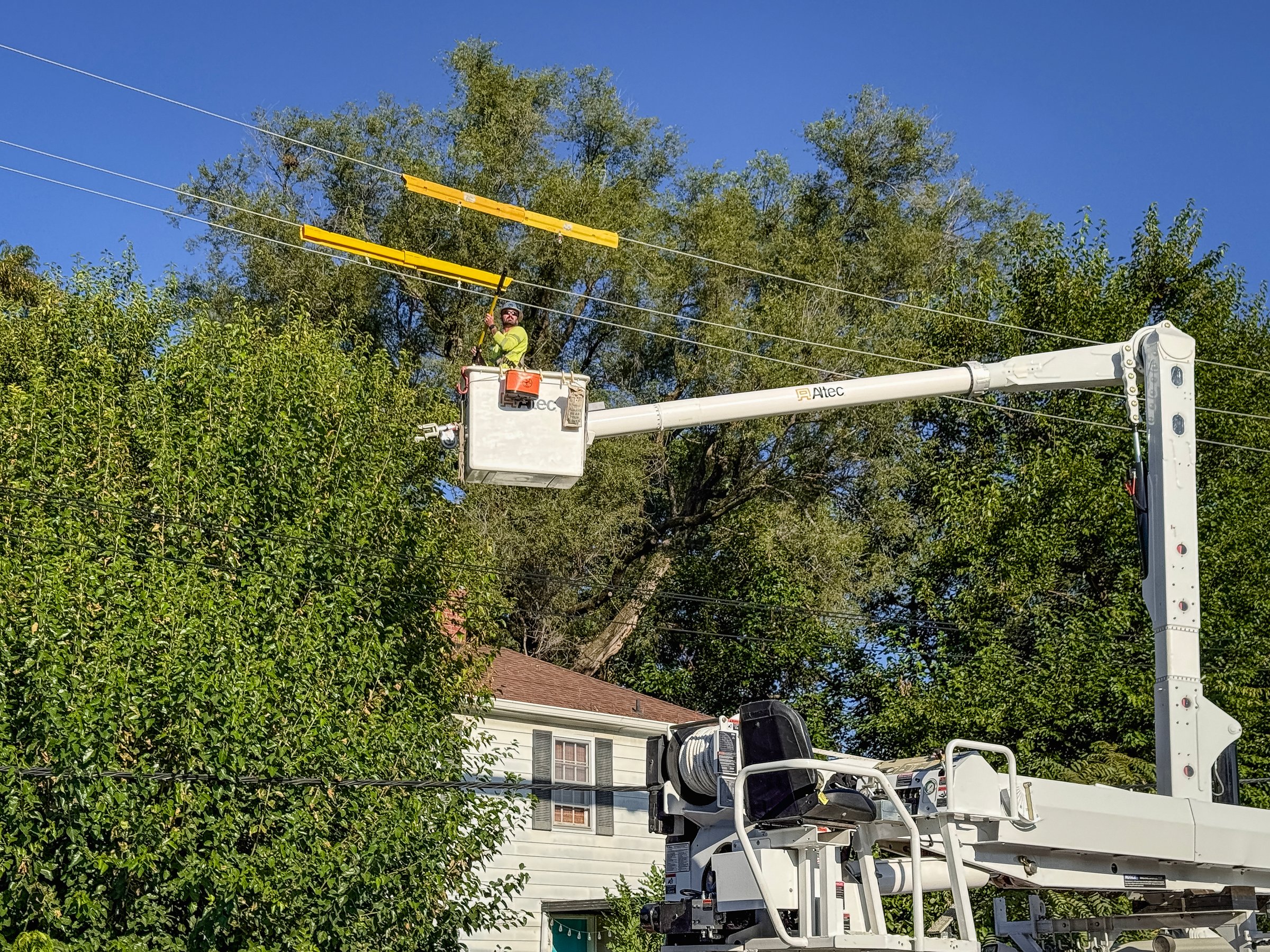 Springfield, Illinois, USA : September 8, 2025 Lineman crews work on adding a new pole to an existing power line. Crews are lifted high into the sky on a mobile crane. Residential area.