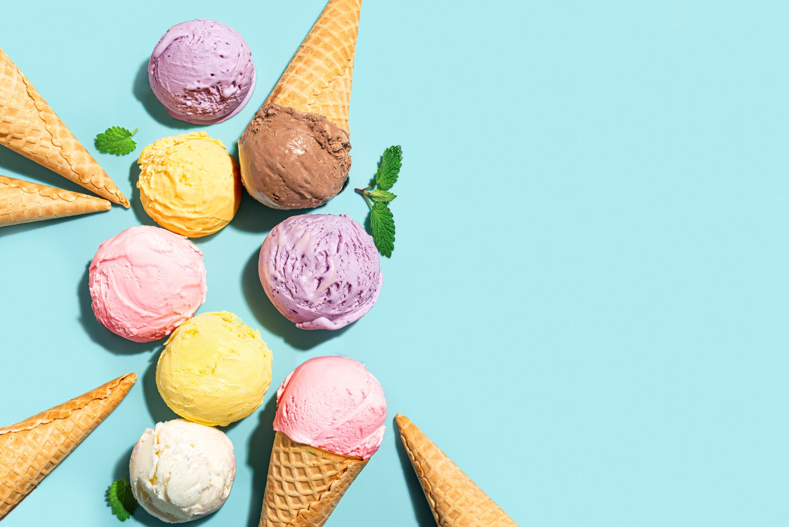 Assorted scoops of ice cream and waffle cones creative layout on blue background, top view, copy space. Various ice creams or gelato trendy design template.