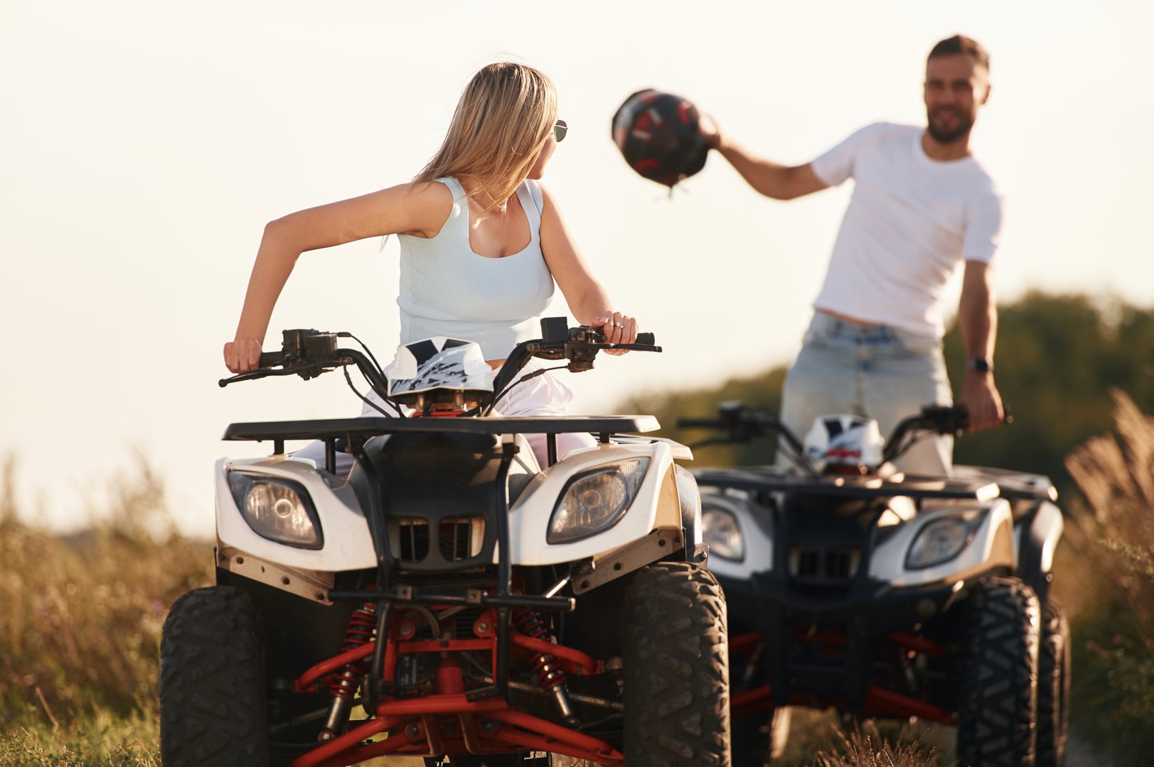 Enjoying the ride, on the field. Man and woman are on ATV outdoors.