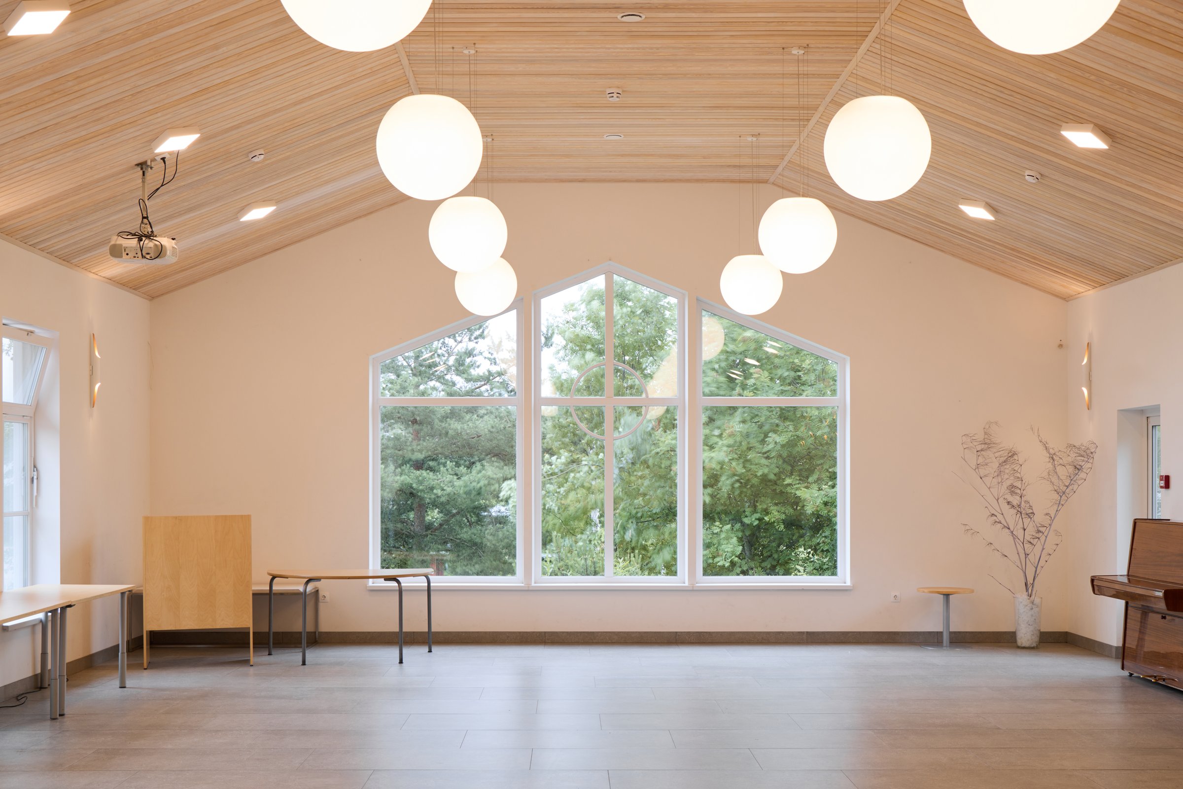 A modern community hall with large windows for natural light and elegant pendant lights that enhance the ambiance