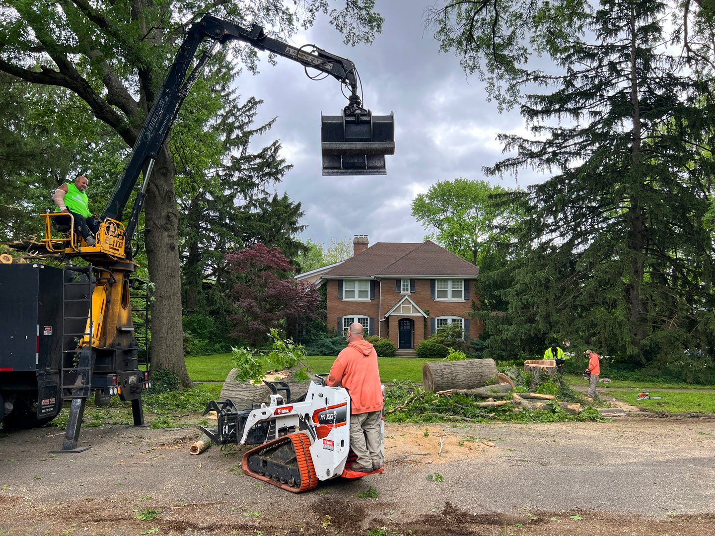 Springfield, Illinois, USA : May 21, 2025 Environmental cleanup following a natural disaster. Crew uses heavy equipment to remove a large tree that has fallen following severe storms. Residential neighborhood on a city street.