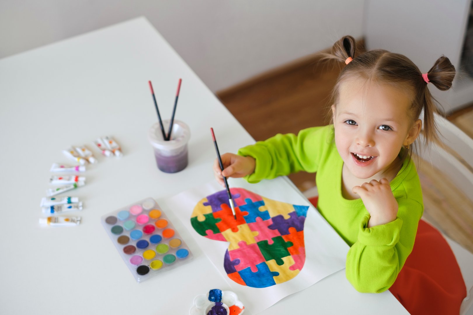 A funny  curious comical girl draws a postcard for children with autism syndrome. Teach children tolerance from childhood. Watercolor multi-colored paints