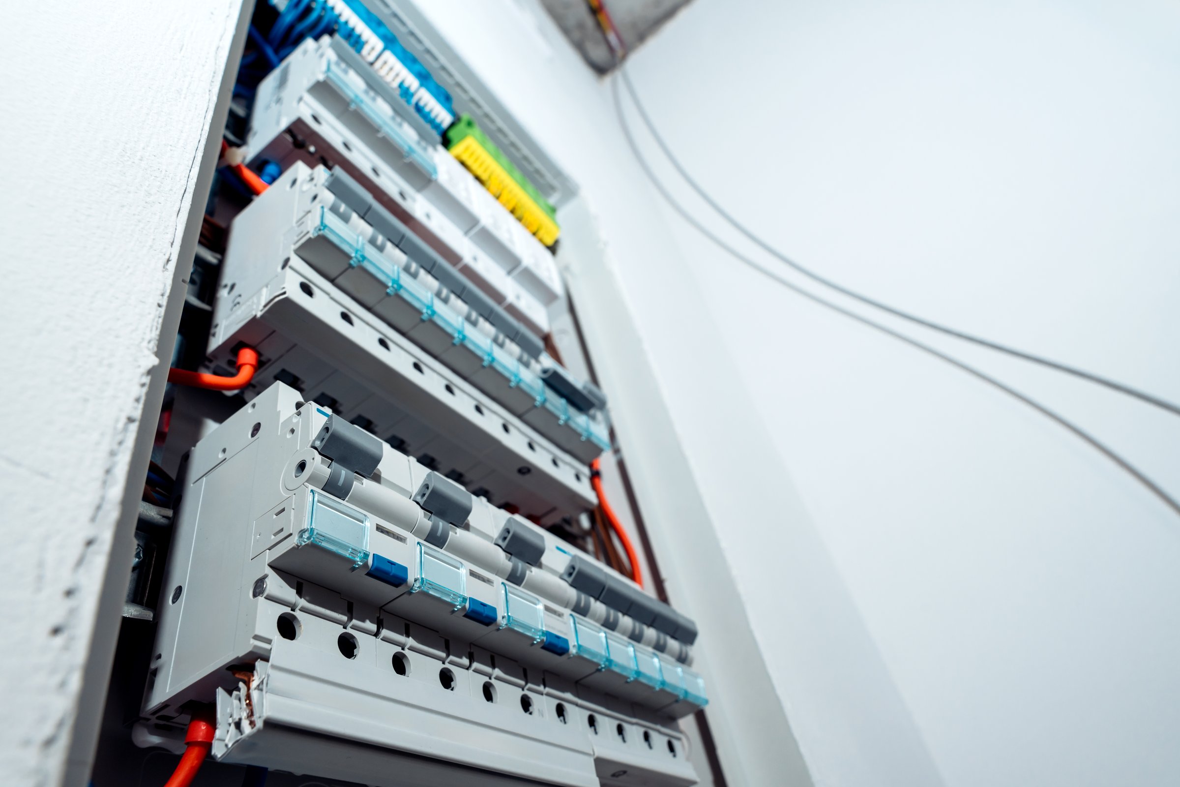 Electrical panel with multiple automatic circuit breakers and connected wires, modern power distribution system in residential building. Background with copy space.
