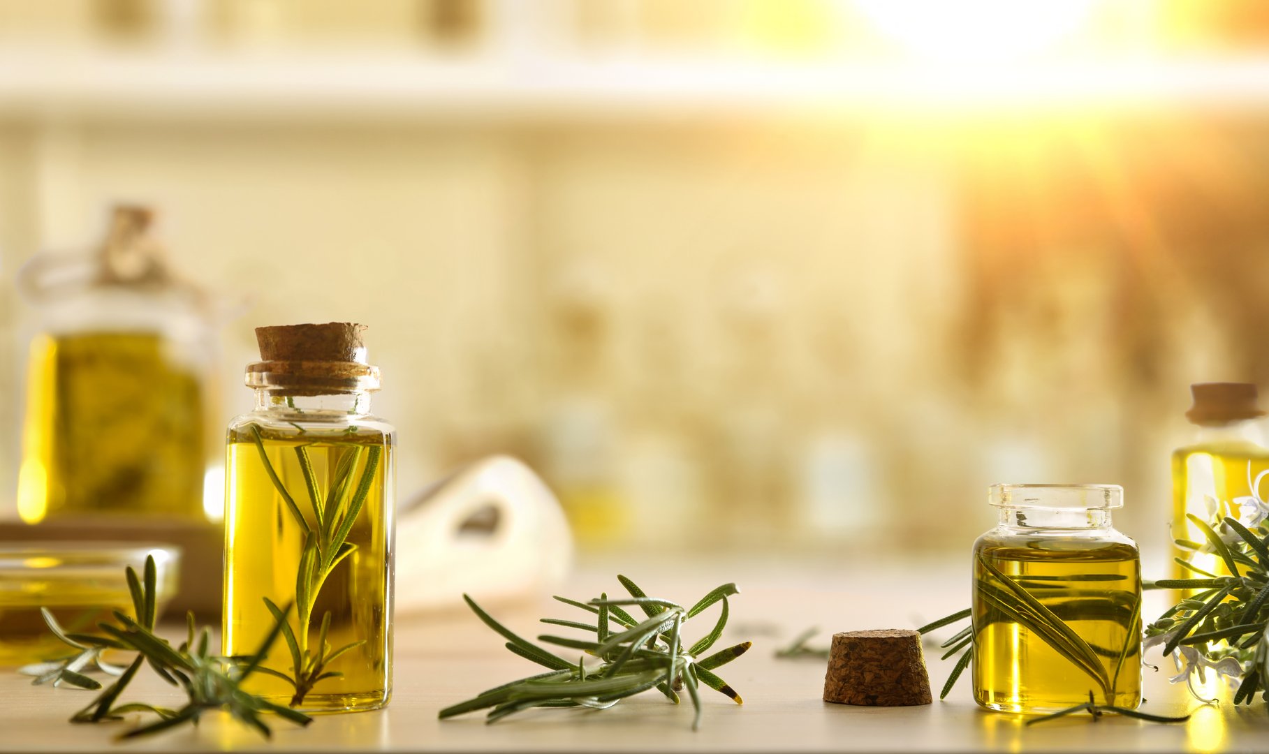 Rosemary essential oil in glass bottles with fresh twigs on wooden table. Front view.