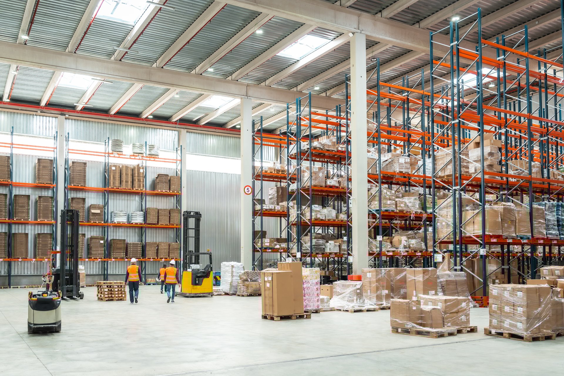Logistics specialists are working inside a large distribution warehouse, managing inventory and preparing goods for shipment