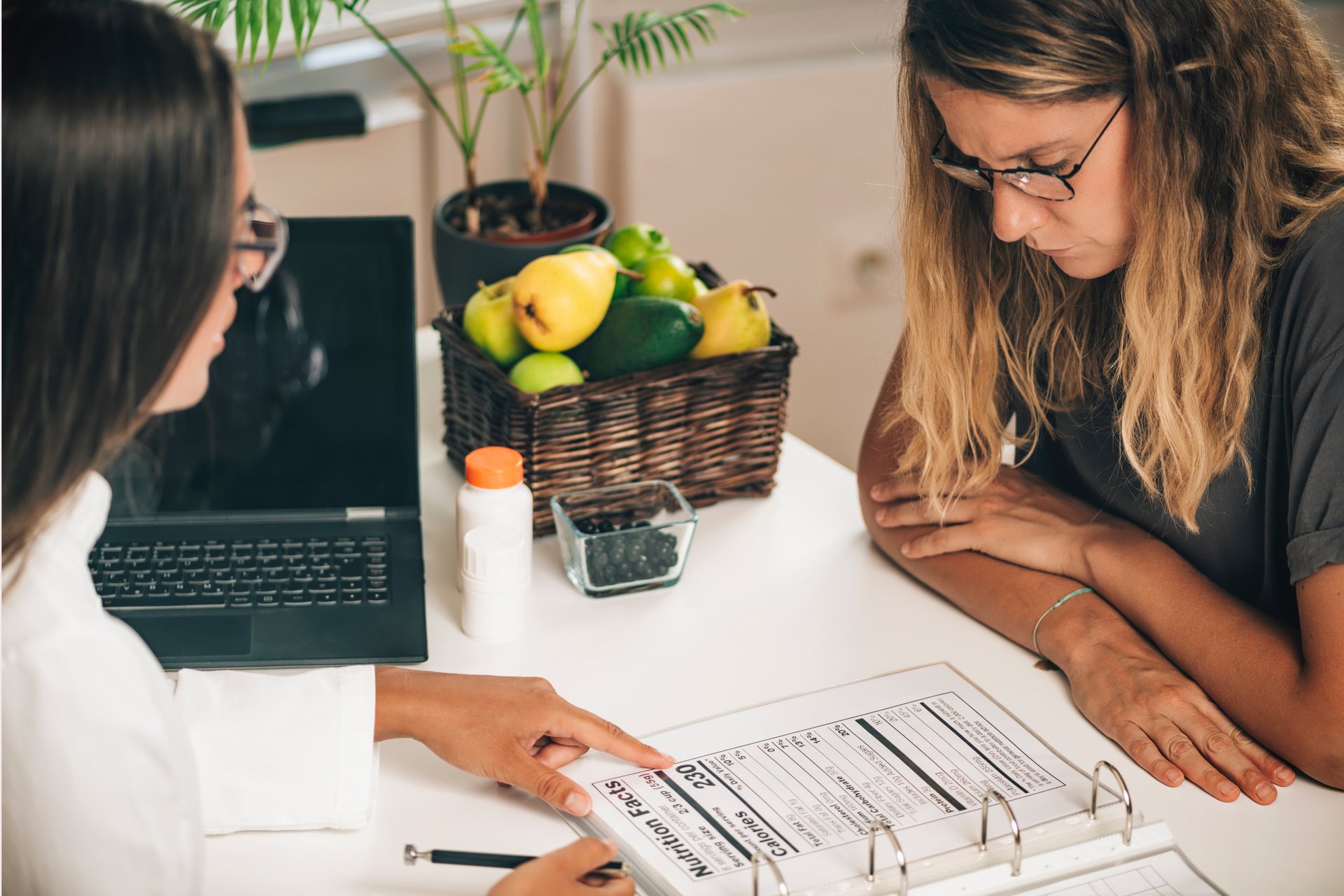 Dietician explaining nutritional facts label to client at weight loss clinic