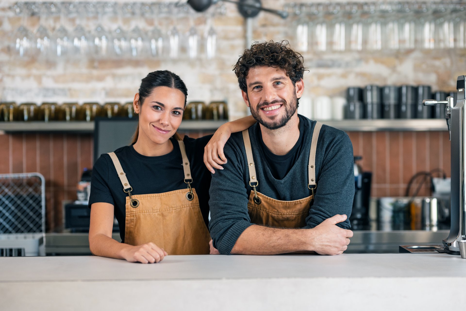 Portrait of two younger waiters looking at camera in a pastry shop.