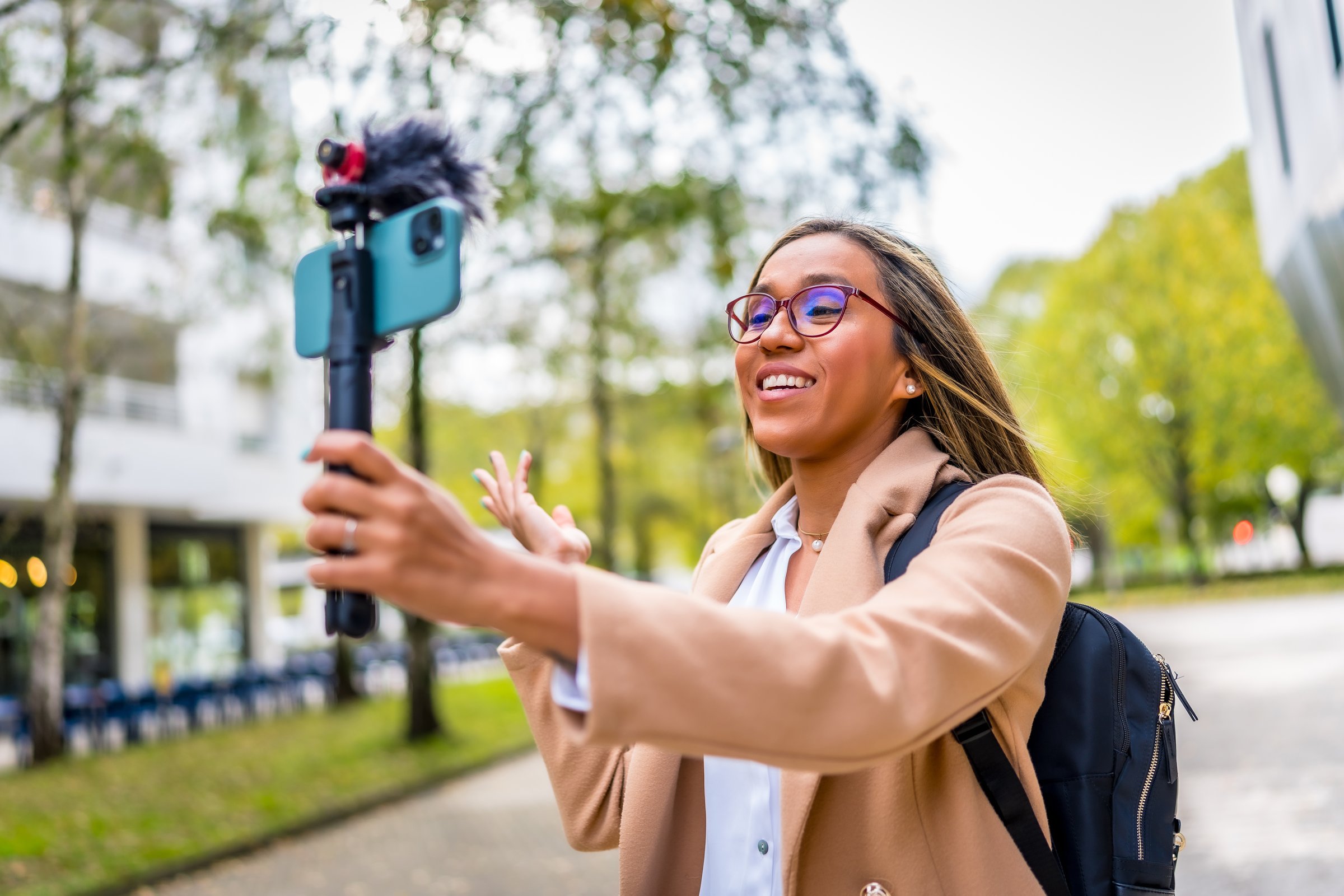 Cool latin woman streamer recording video blog explaining something to the camera in the city
