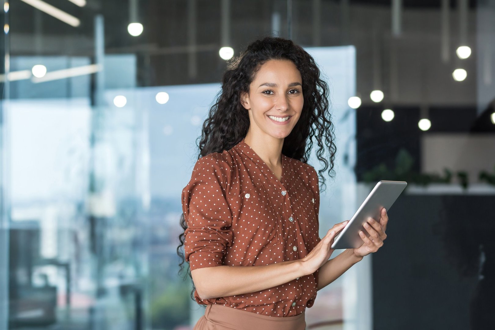 Young and successful female programmer, portrait of female engineer with tablet computer startup worker working inside office building using tablet for testing applications smiling looking at camera.