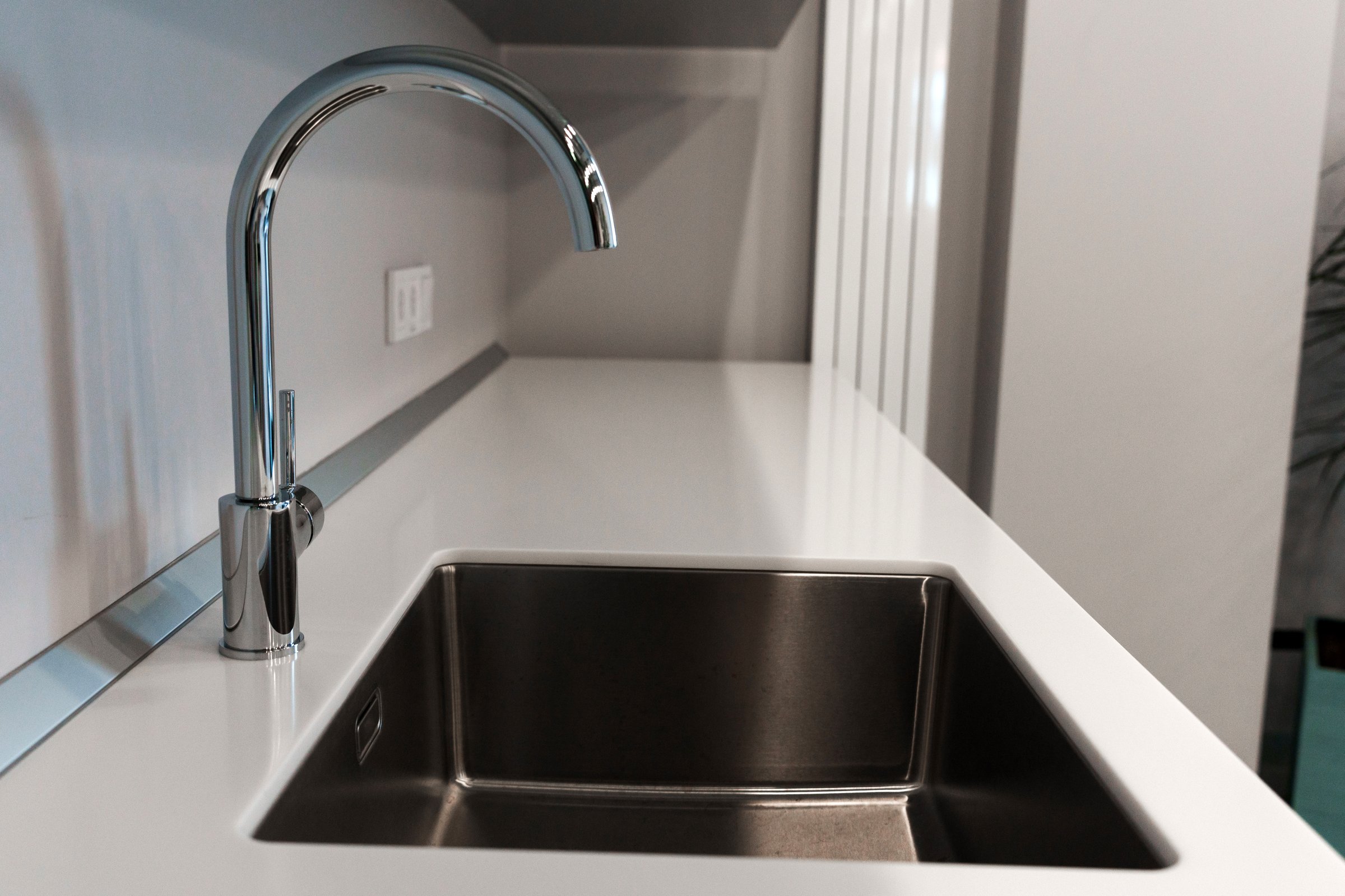 The kitchen sink with a mixer is clean in the kitchen