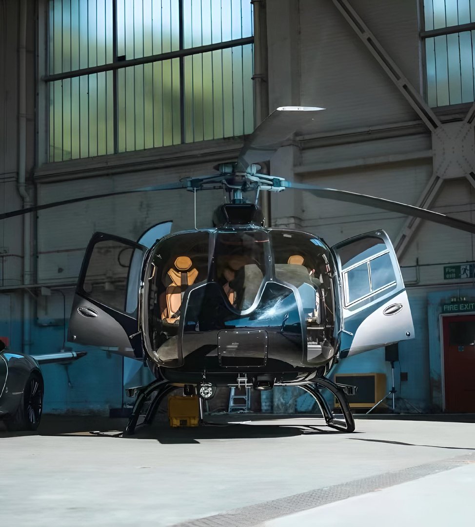A helicopter parked in a hangar with a car nearby