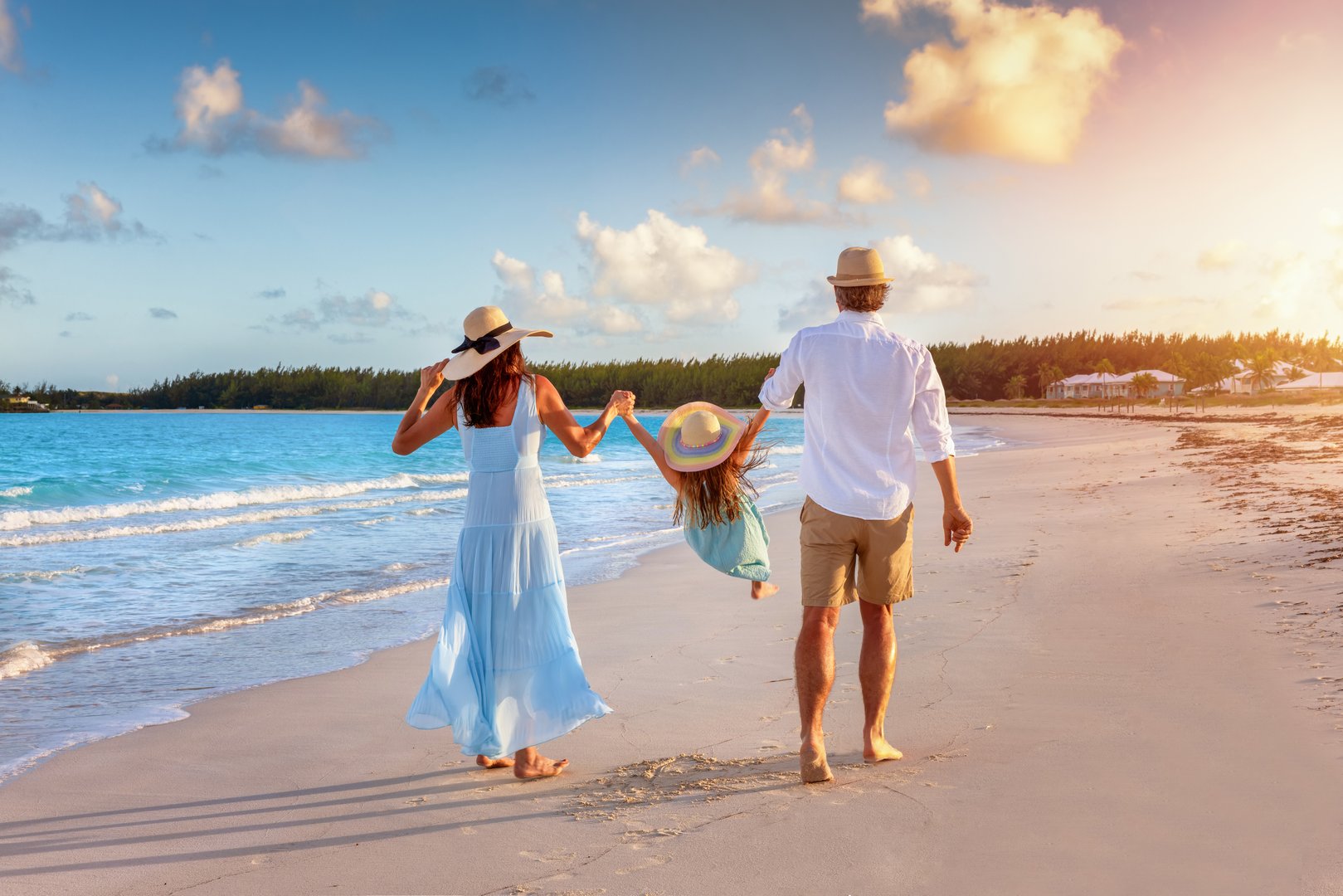 A happy family in walks hand in hand down a tropical beach during sunset time and enjoys their summer vacation time