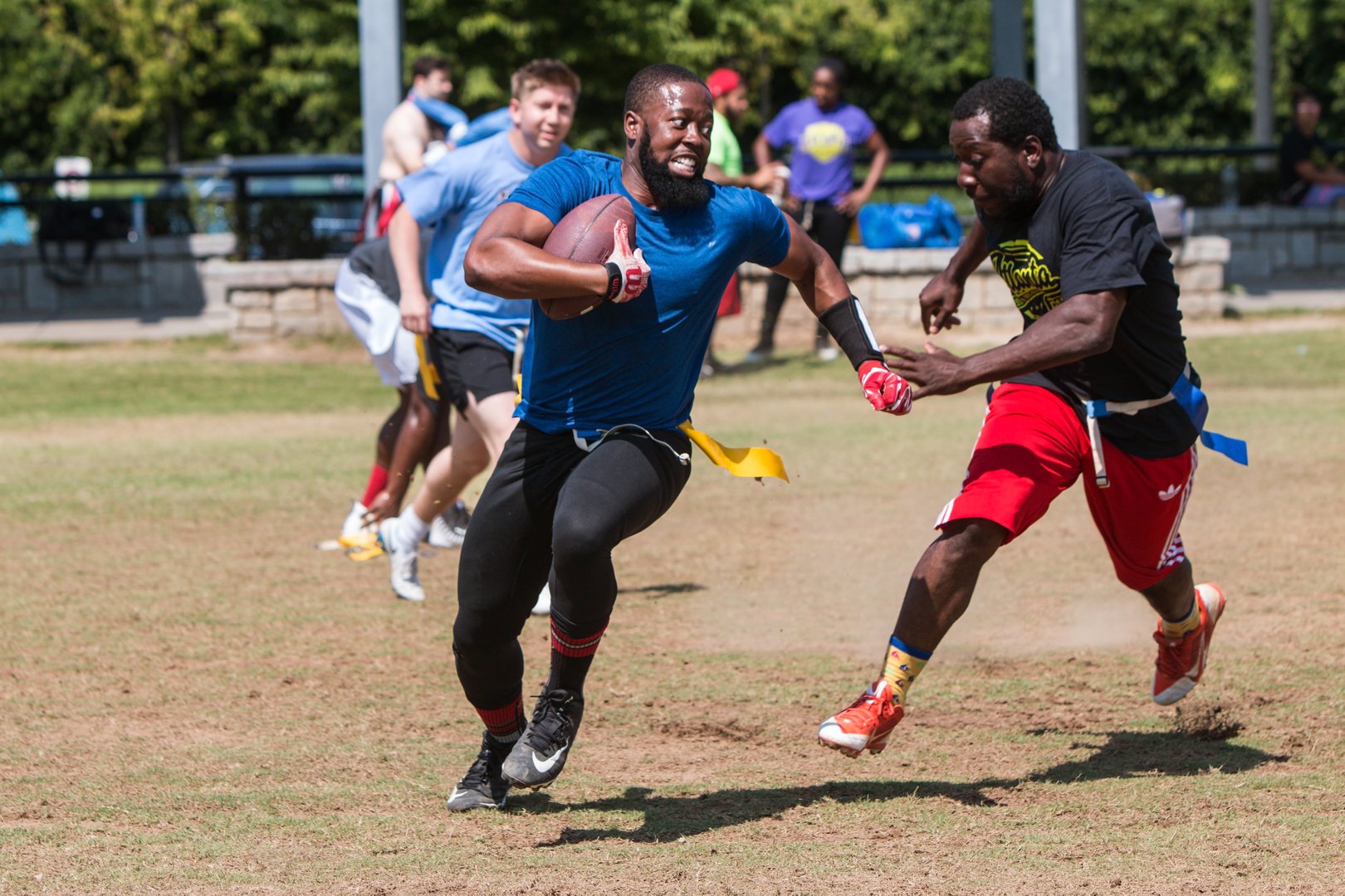 Atlanta, GA, USA - June 1, 2019:  A man carrying the ball tries to run away from a defender in a recreational league flag football game played at the Old Fourth Ward Park on June 1, 2019 in Atlanta, GA.