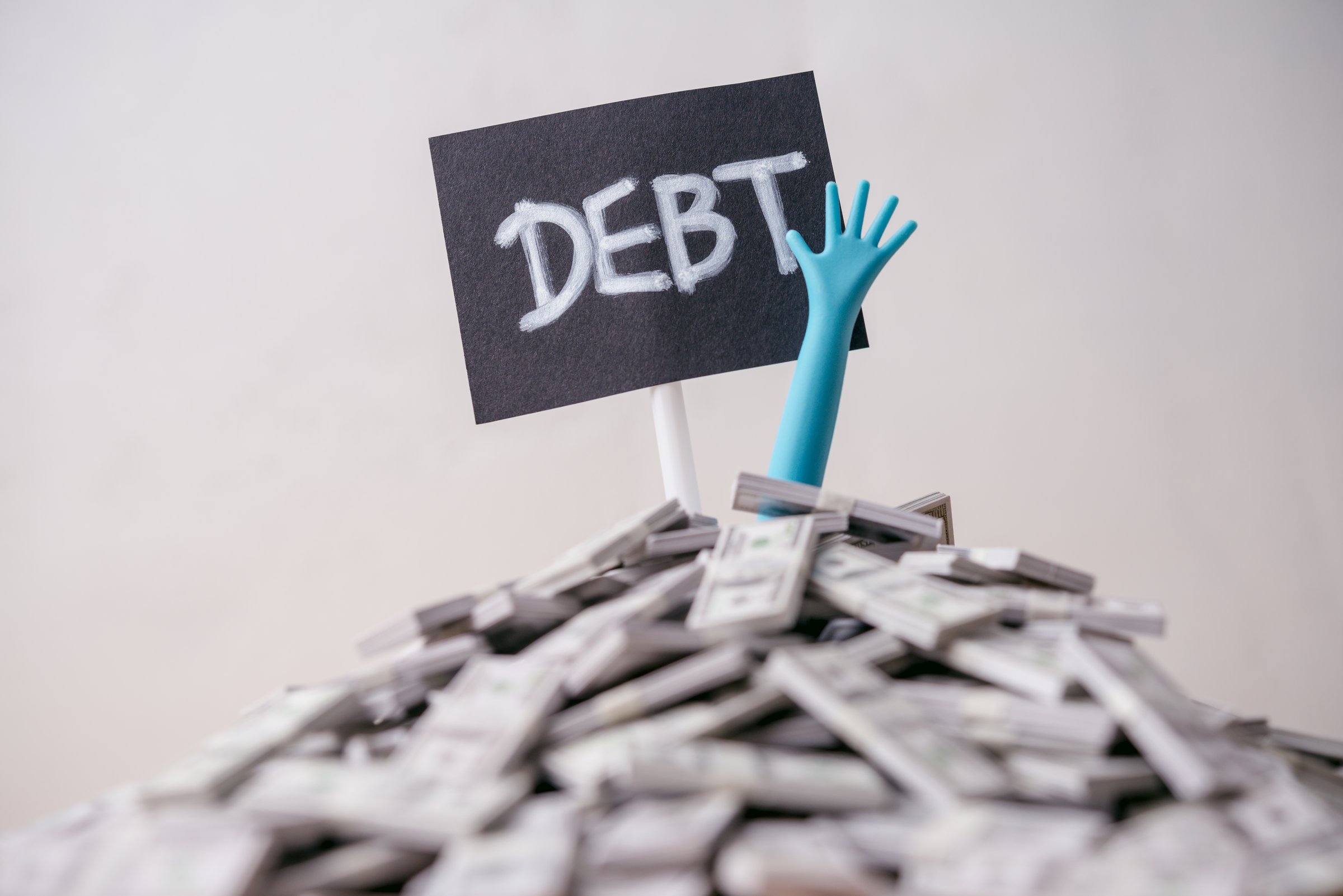 Hand reaching from dollar banknotes with DEBT label