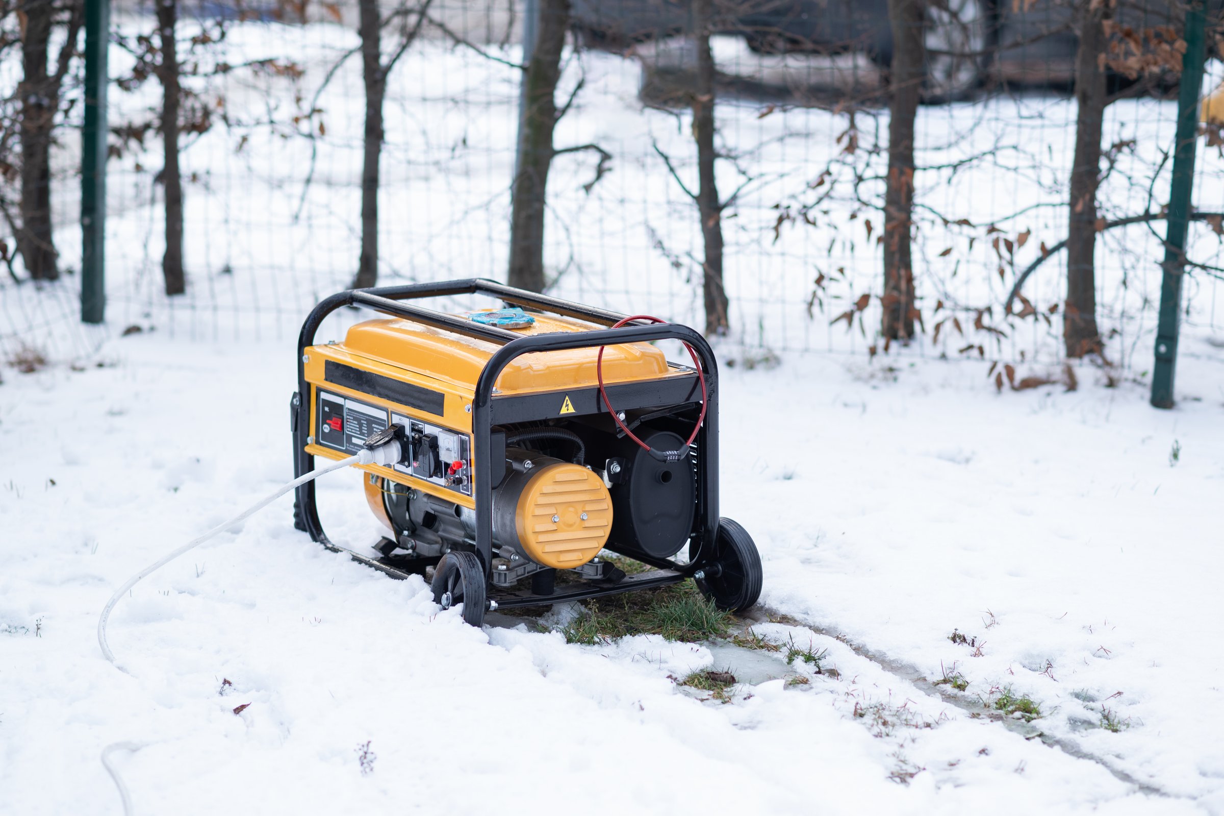 Yellow portable gasoline generator providing backup power in a snowy outdoor setting during winter.