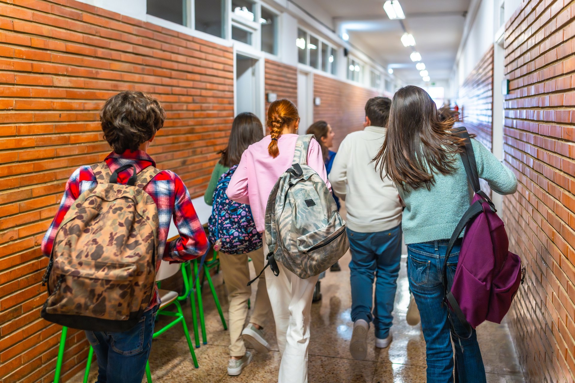 Group of students rushing through a school hallway, carrying backpacks and chatting excitedly as they transition between classes