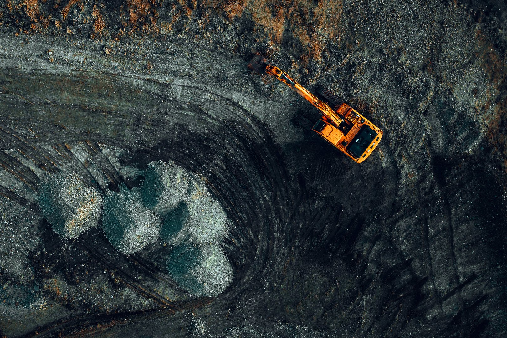 Bright excavator at work on a dark background view from a drone