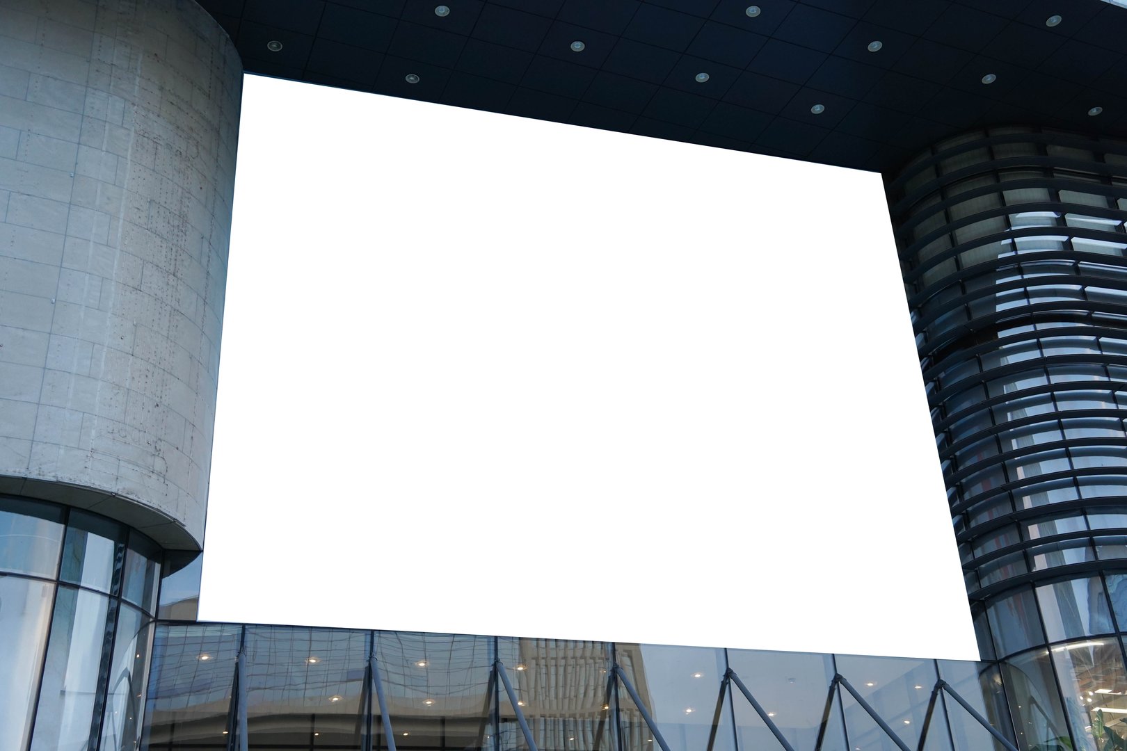 A mockup of a blank white billboard framed by a modern building facade, ideal for advertising