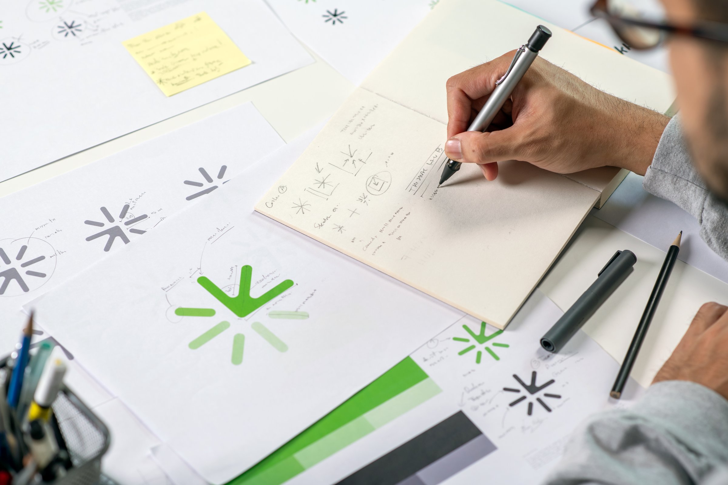 Close-up shot of a graphic designer making notes on logo designs, designing logos, and showcasing the corporate identity and logo design process.