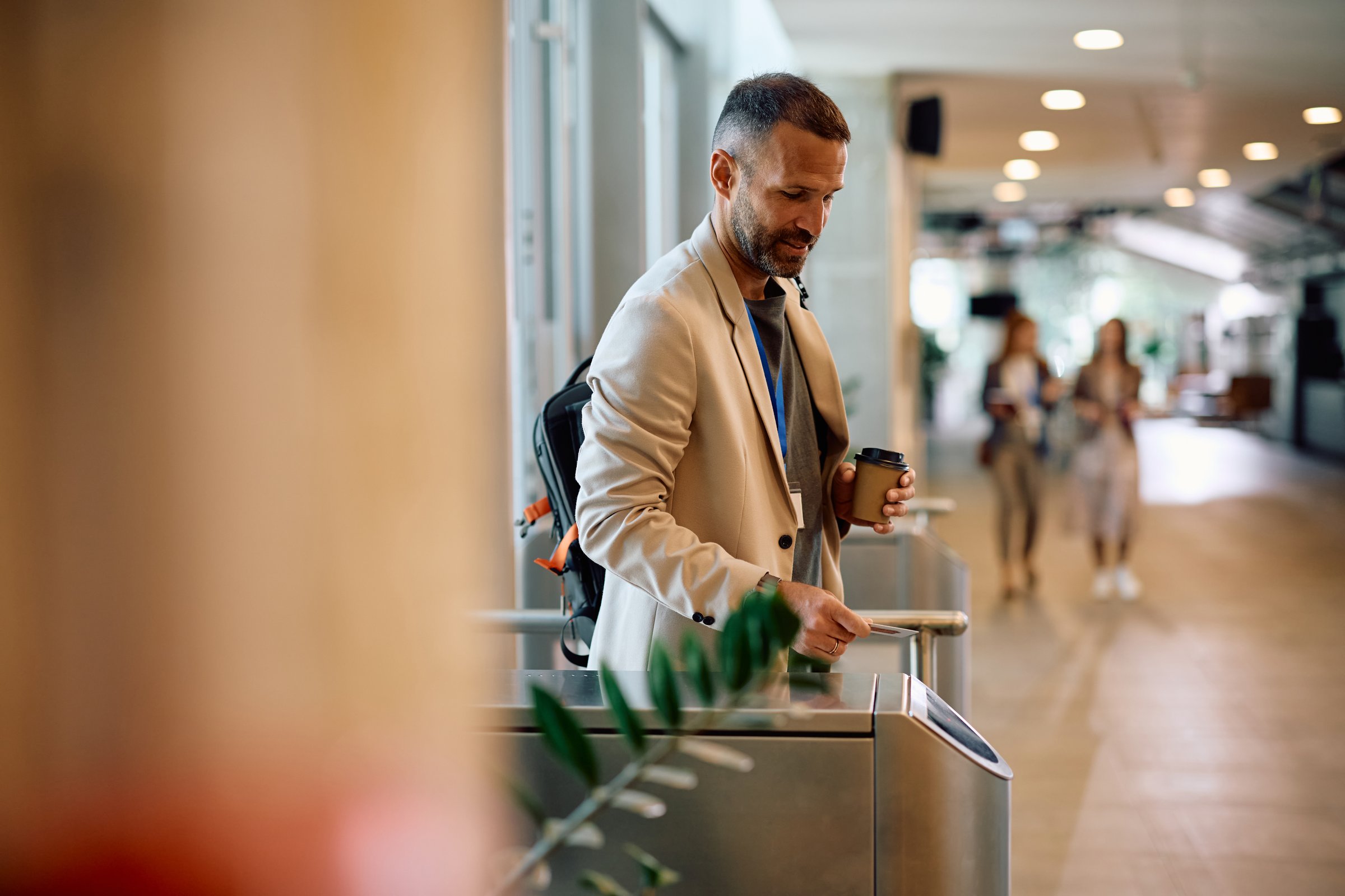 Smiling businessman using smart card while  coming to work in the office. Copy space.