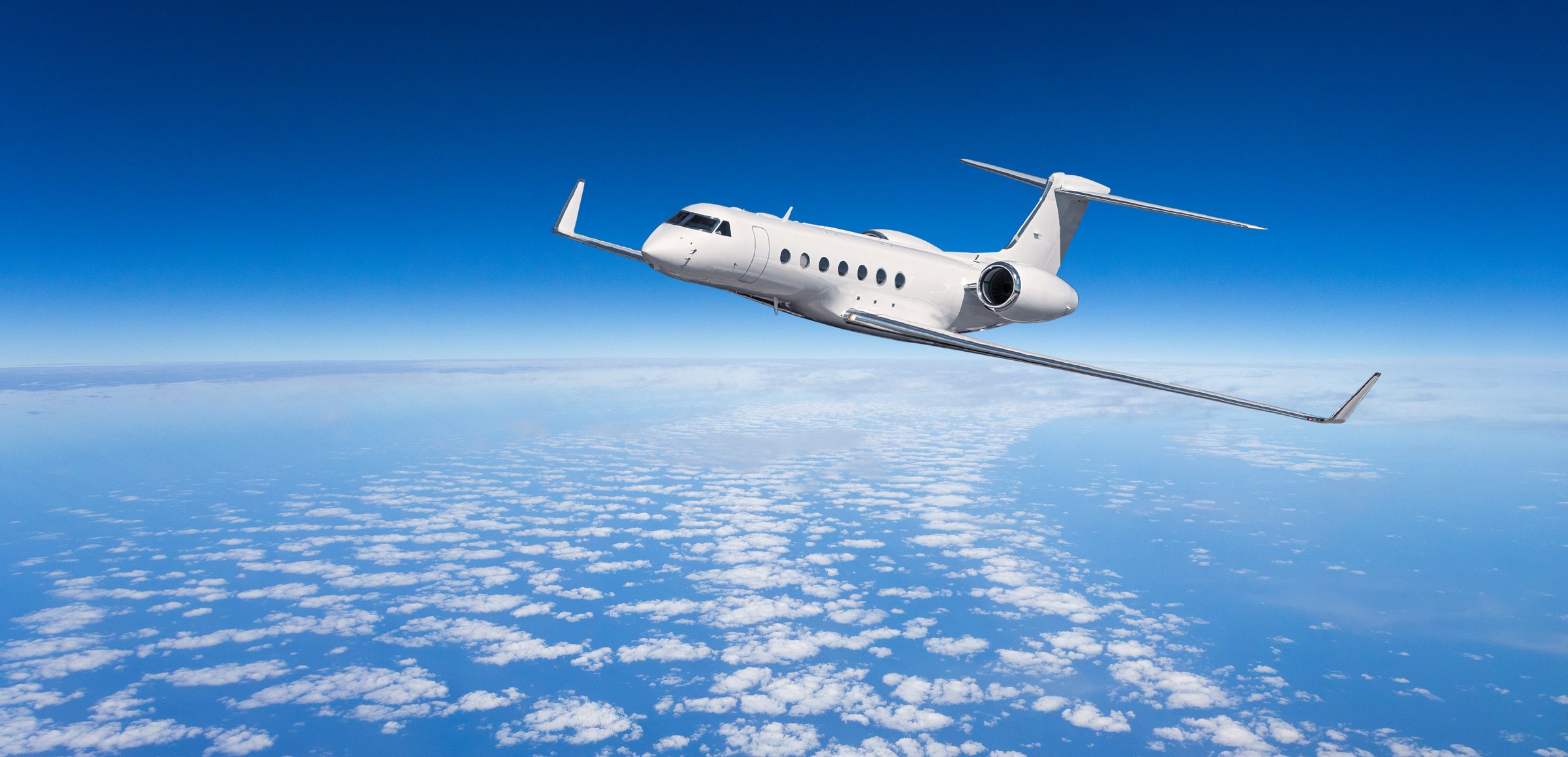 Luxury private jet cruising above a beautiful cloudscape, symbolizing comfortable and fast travel