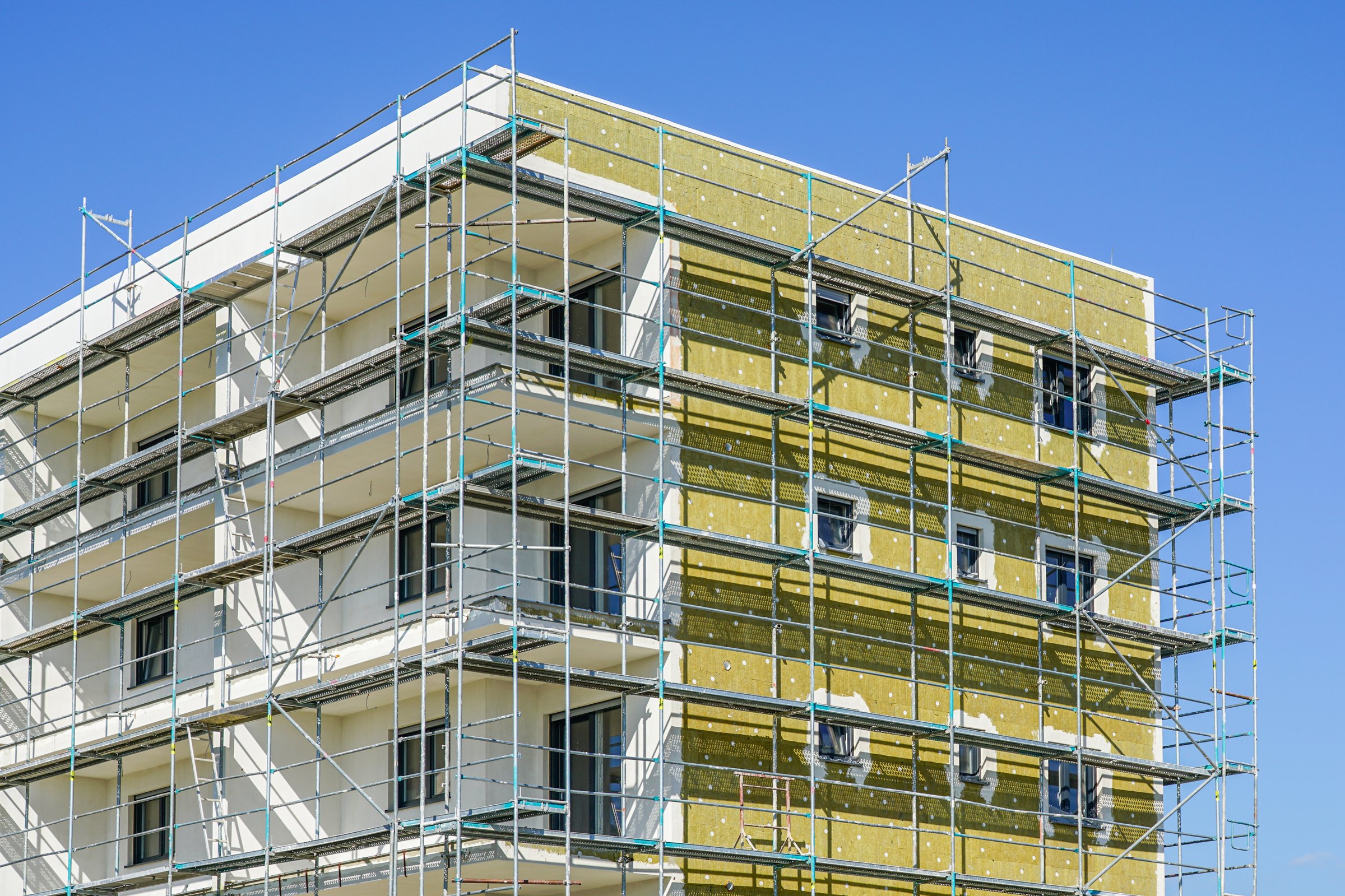Thermal insulation of the facade of a apartment building with mineral wool plates using scaffolding around facade