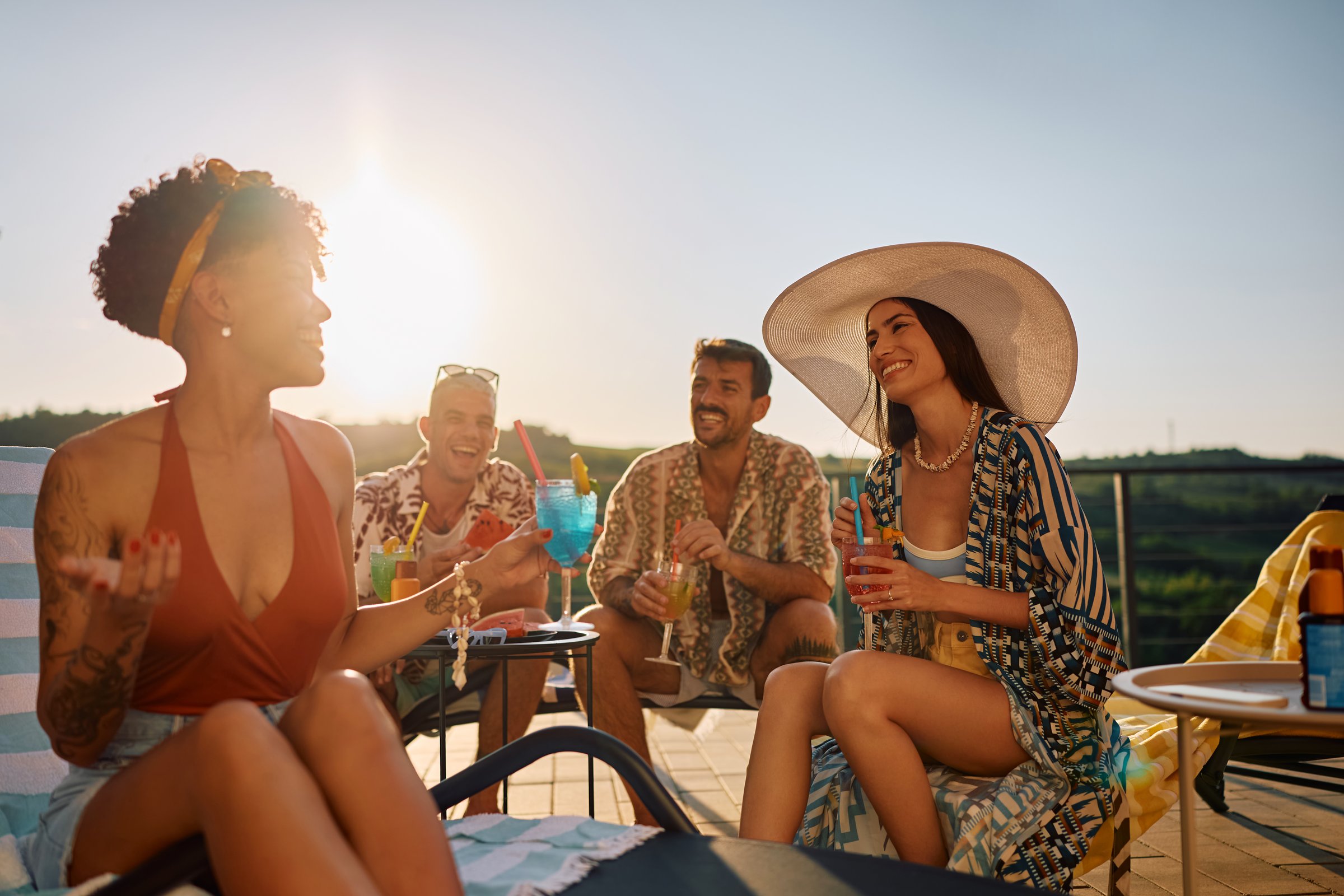 Young happy friends having fun in summer while drinking cocktails and communicating on a patio.