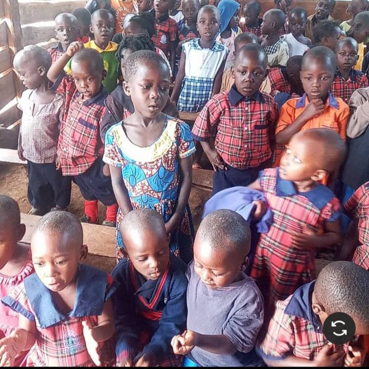 Group of young children in colorful school uniforms standing inside a classroom.
