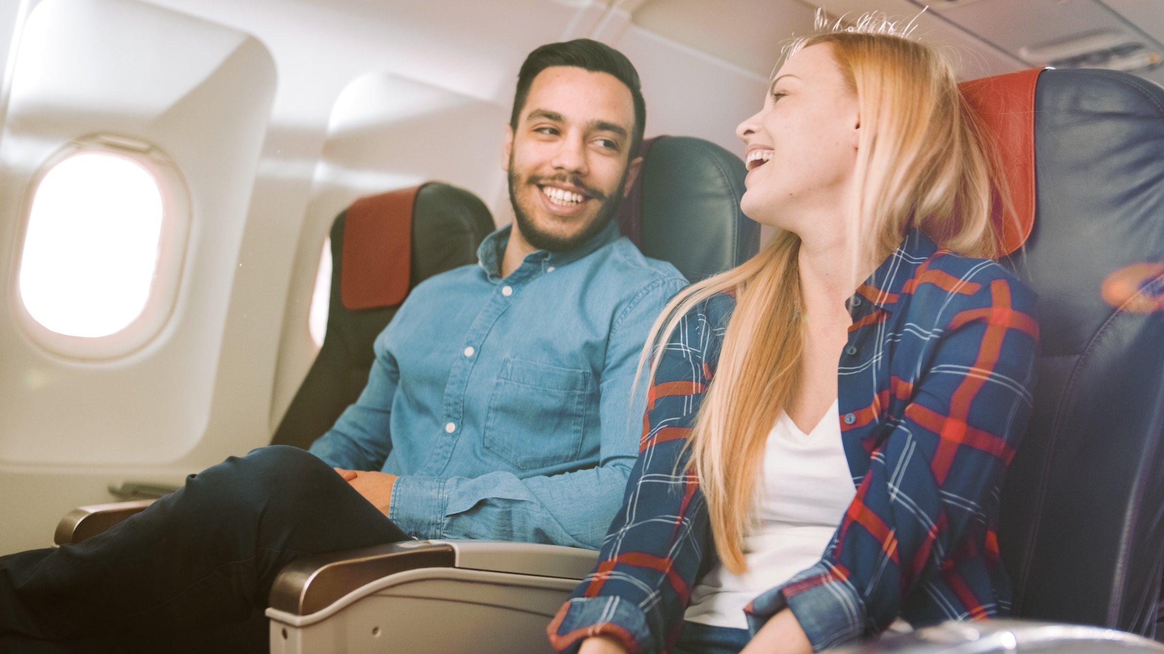 Hombre joven viajando en avión, sentado en su asiento con una sonrisa